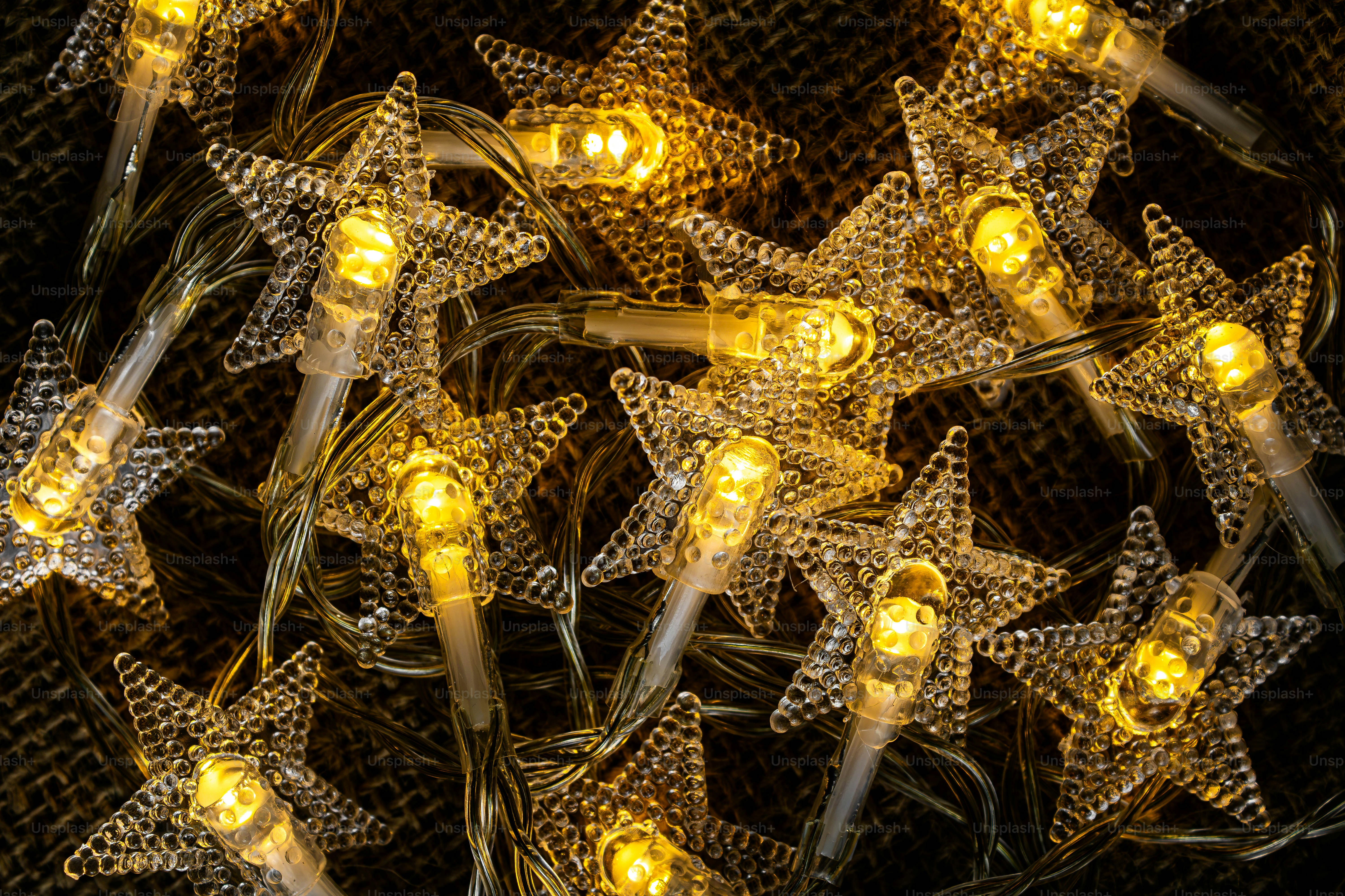 Luces de hadas brillantes en forma de estrella con bombillas amarillas cálidas descansando sobre una superficie texturizada de arpillera marrón
