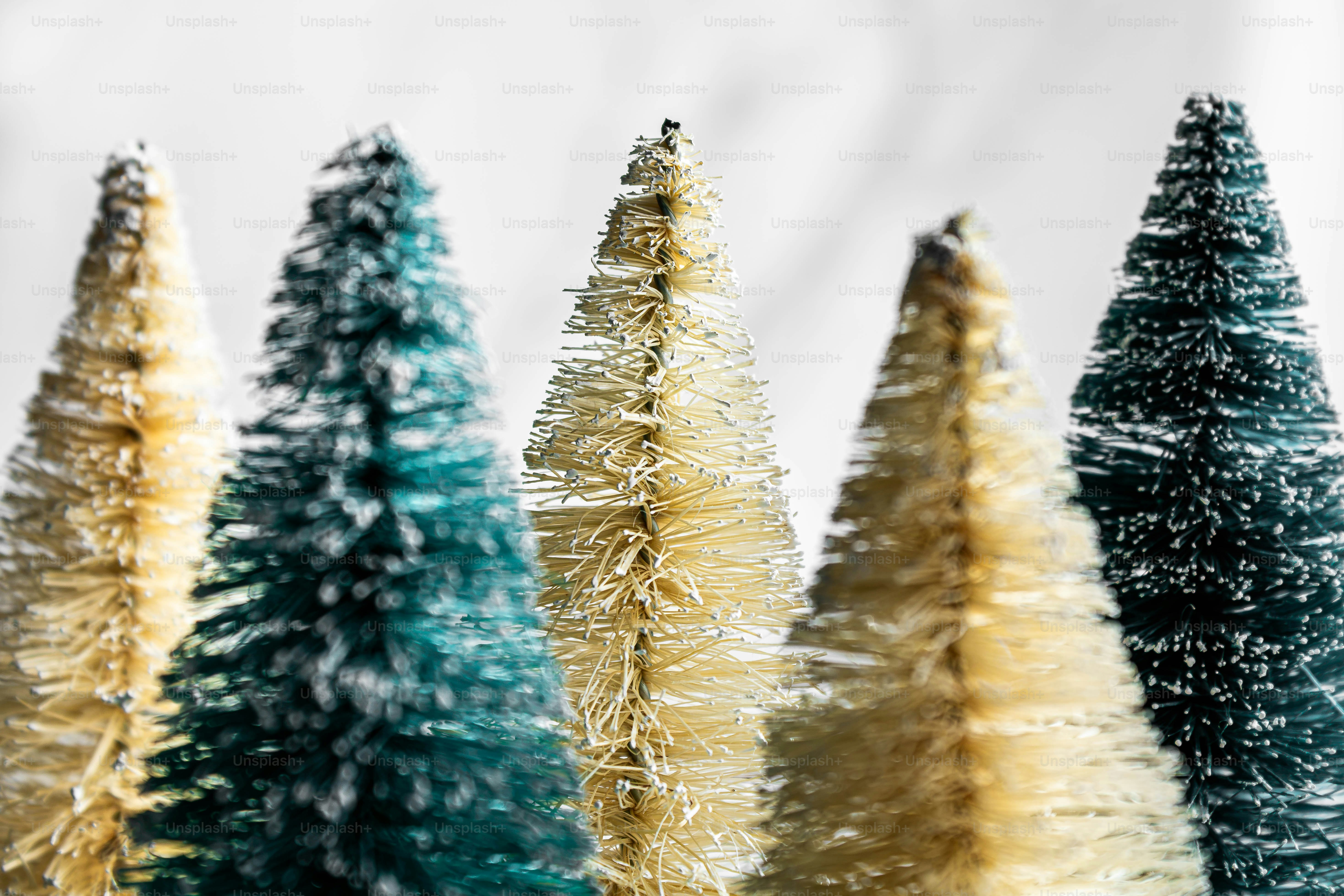 Una fila de pequeños árboles de Navidad con brocha de botella en colores alternados crema y verde oscuro