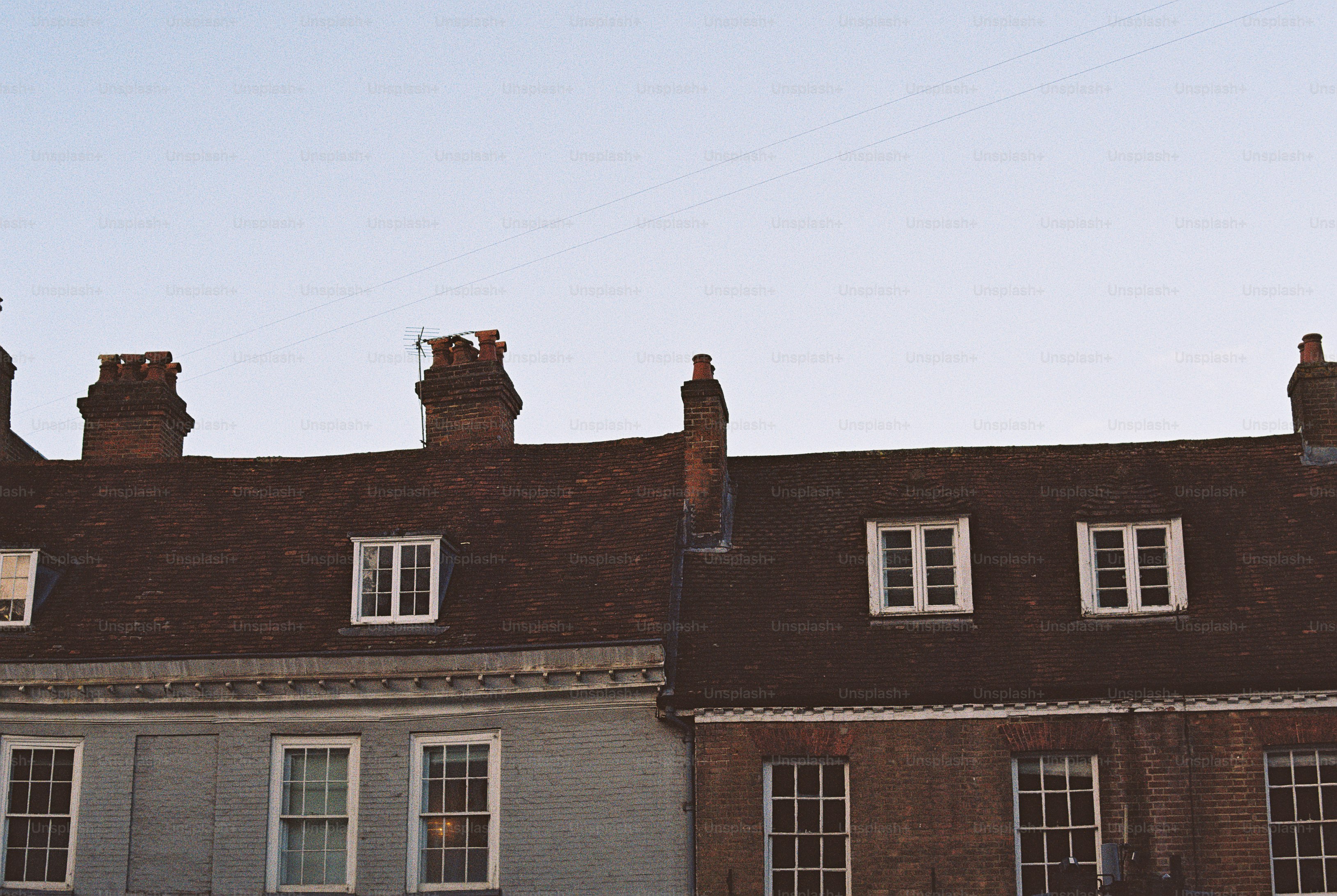 A row of historic brick houses with tiled roofs and chimneys against a clear sky