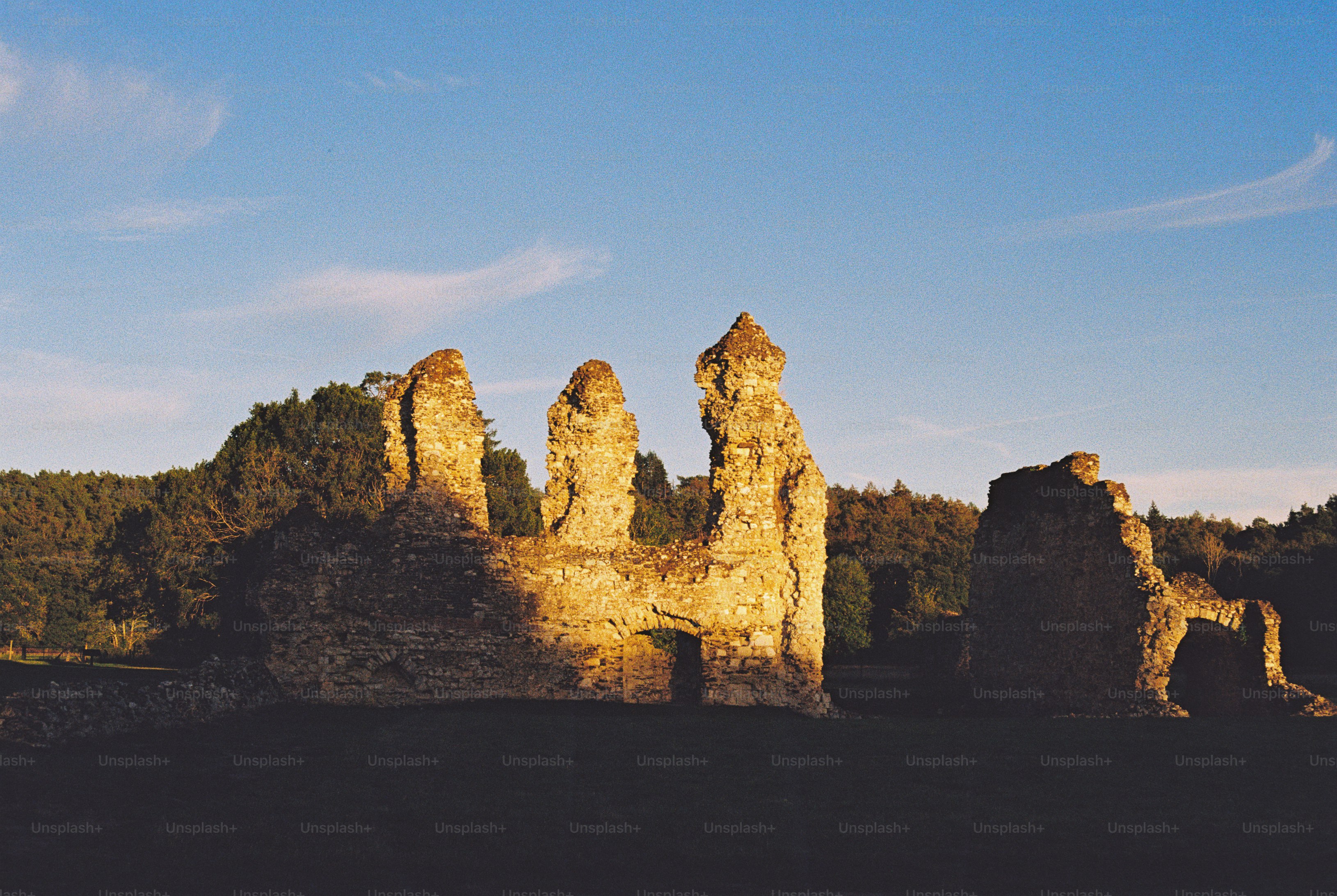 Ancient stone ruins illuminated by warm golden hour light against a clear blue sky