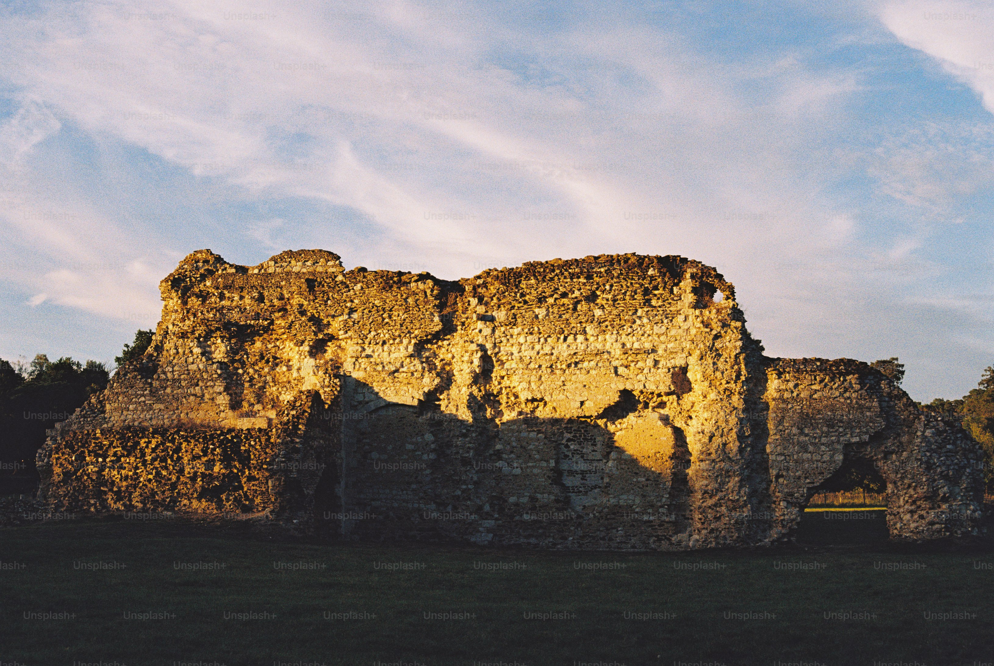 Ancient stone ruins illuminated by warm golden hour light under a blue sky