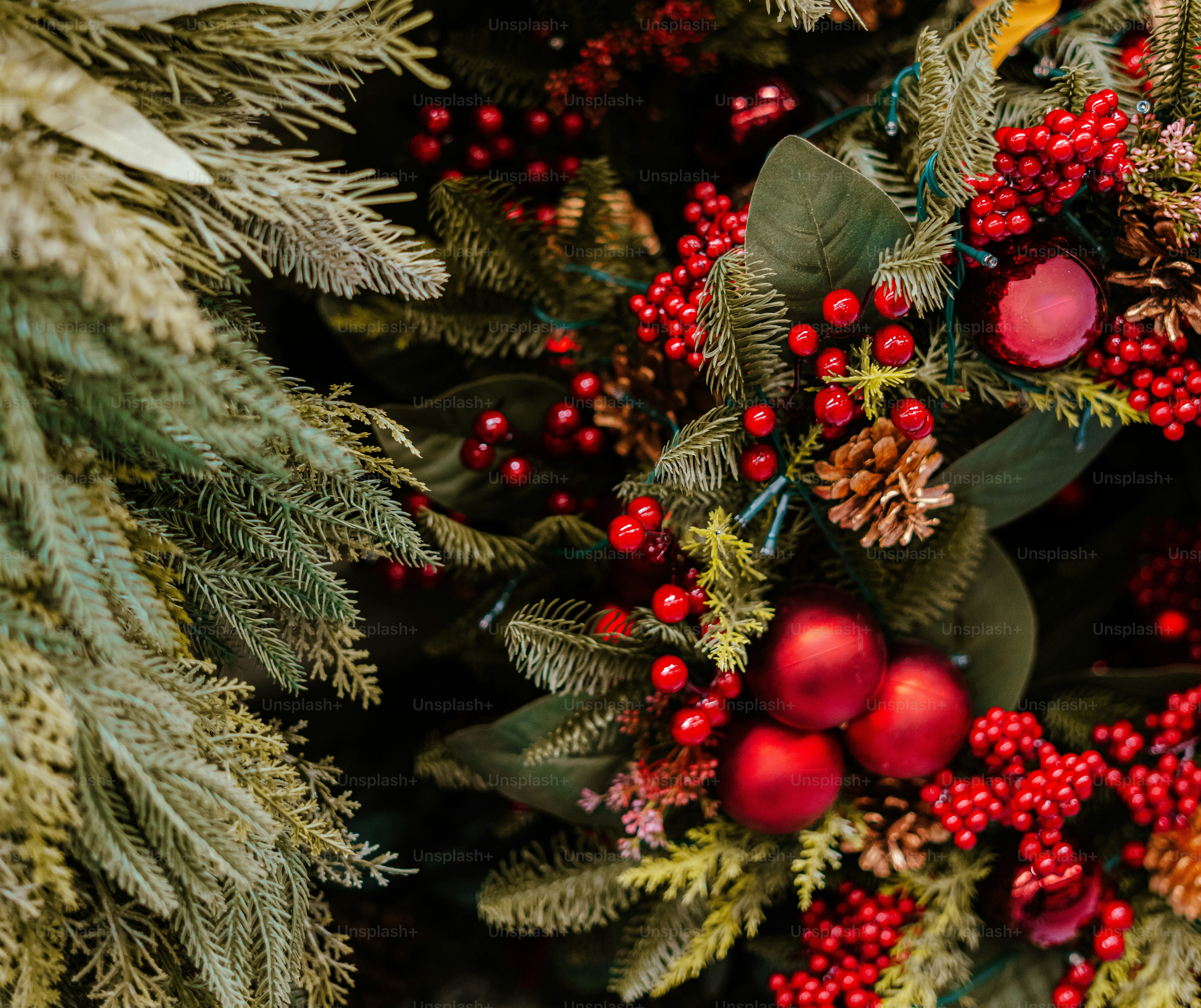 Christmas wreath with red ornaments, pine cones, and holly berries on evergreen branches