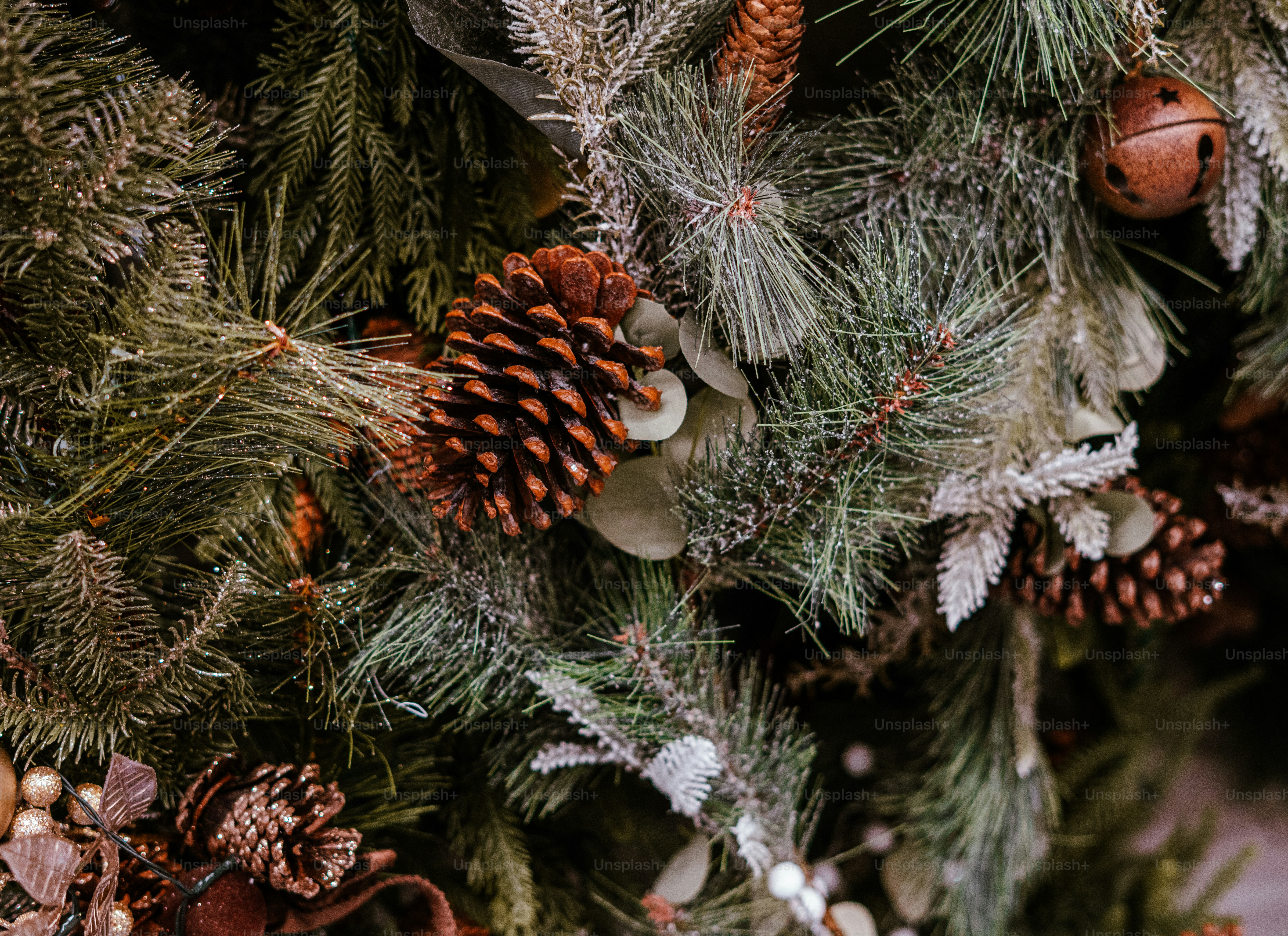 Pine cones and a rustic bell ornament nestled in a festive evergreen Christmas tree