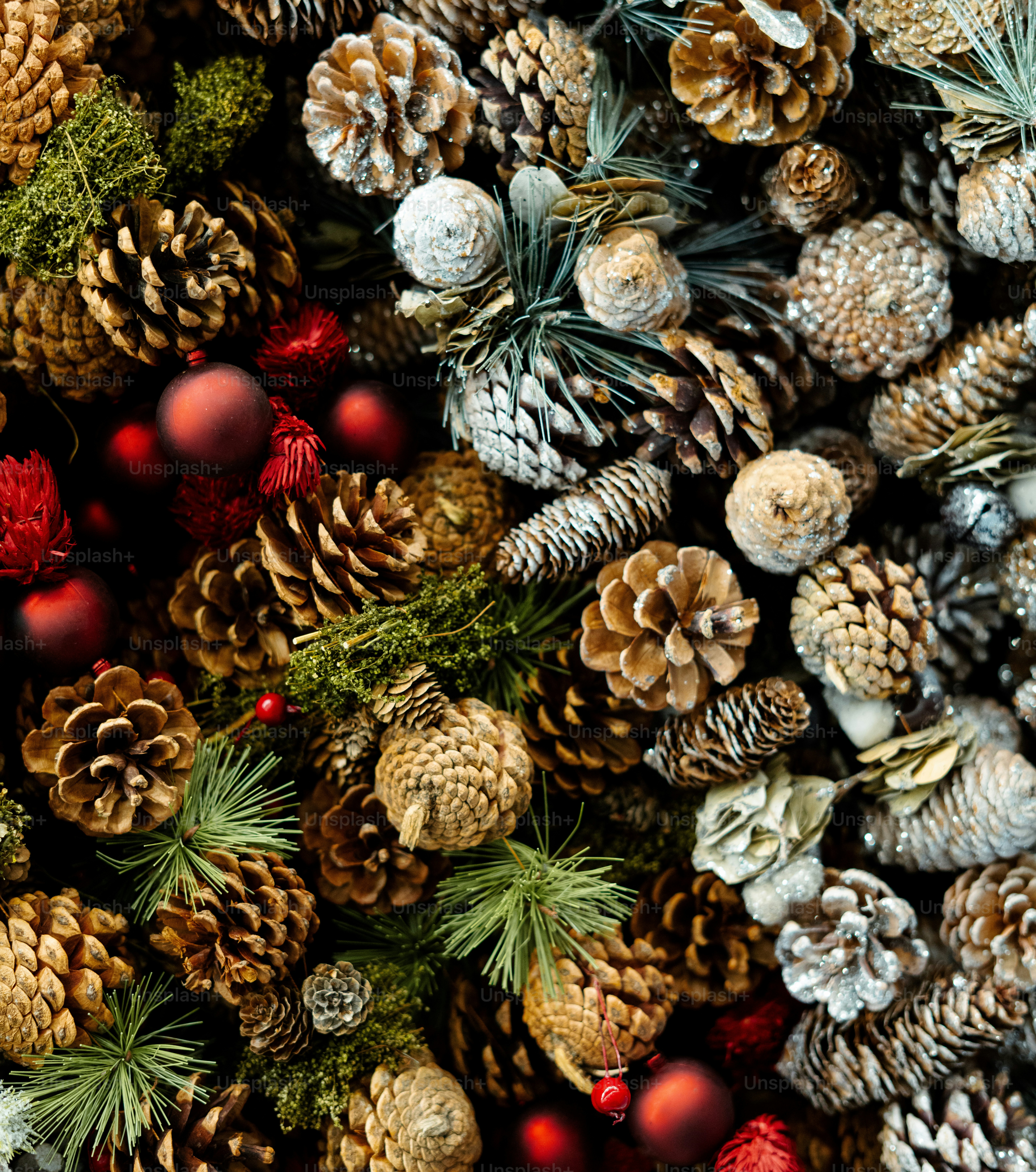 A collection of pine cones, red ornaments, and green pine needles arranged in a festive holiday display