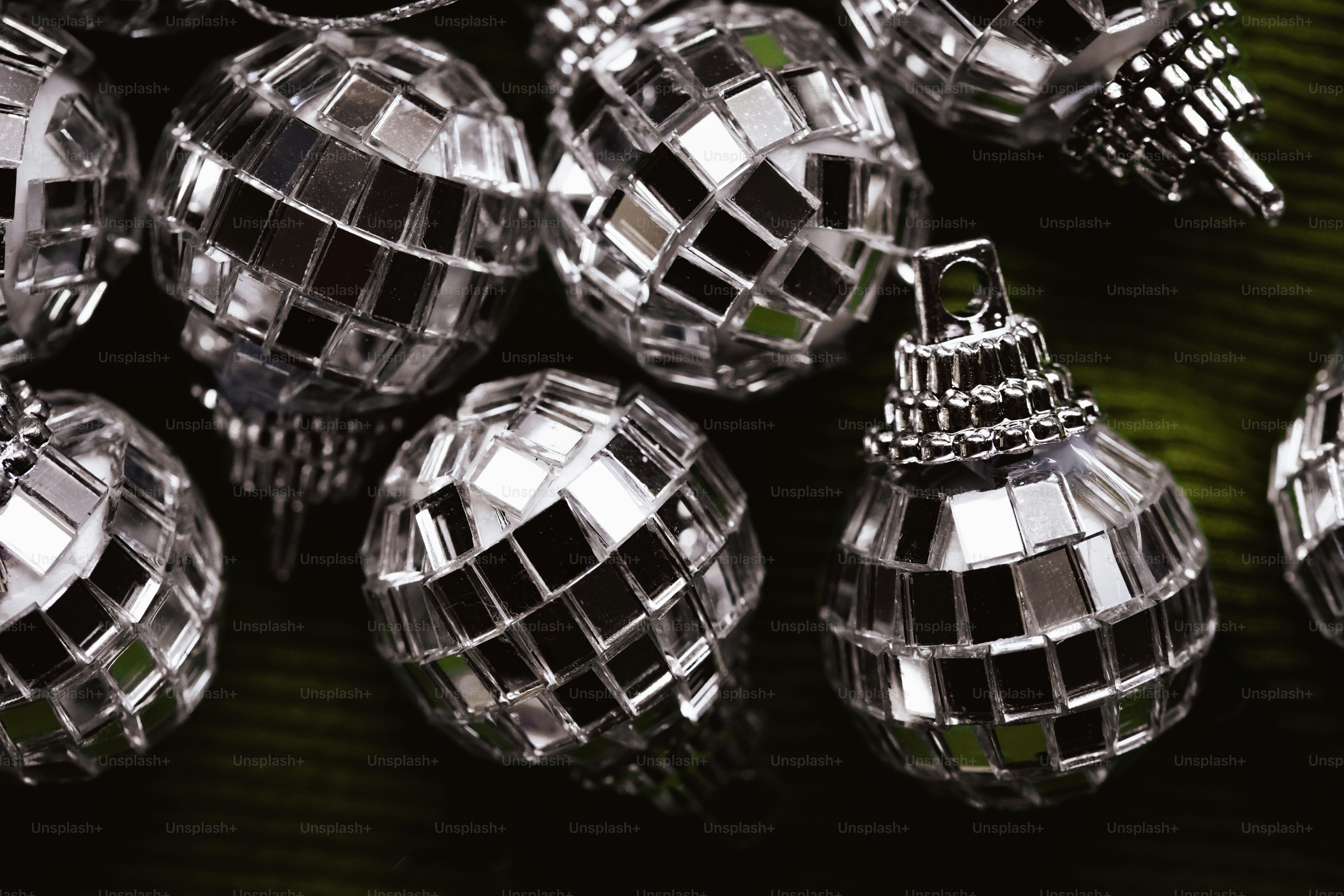 A collection of small mirrored disco ball ornaments resting on a dark green surface