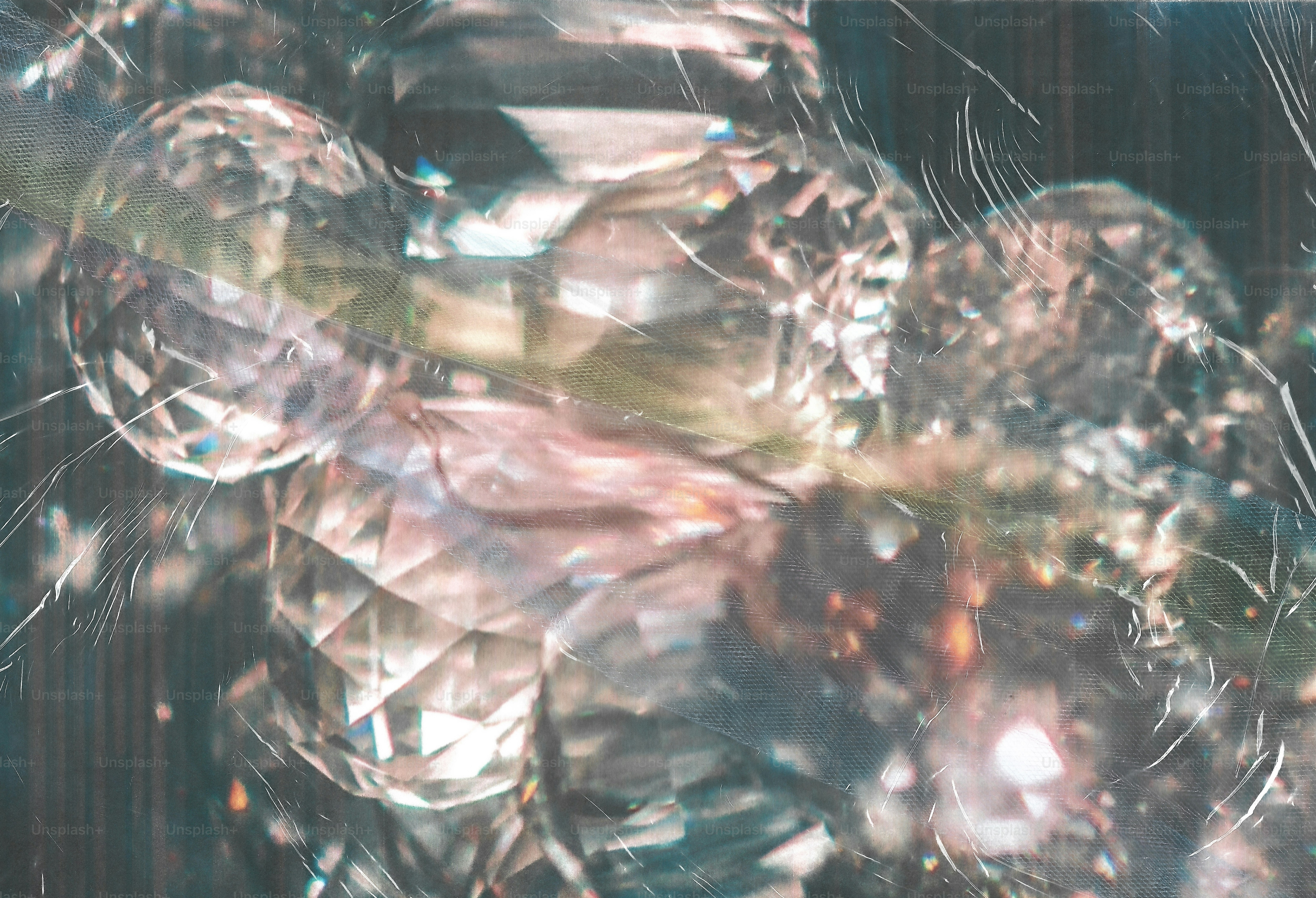 Faceted crystals reflecting light through a translucent fabric overlay with visible scratches