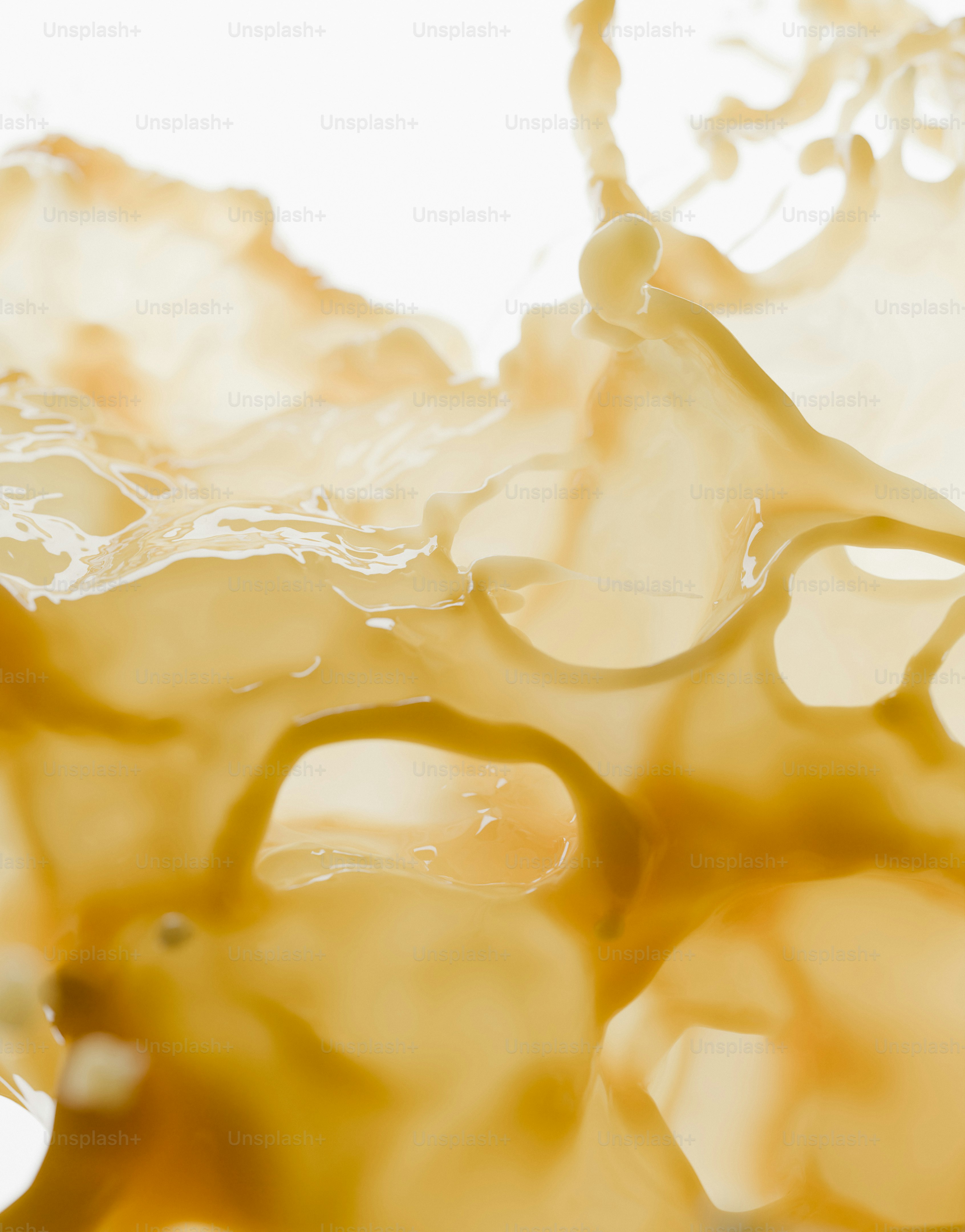 A macro view of a thick beige liquid splashing into intricate organic shapes