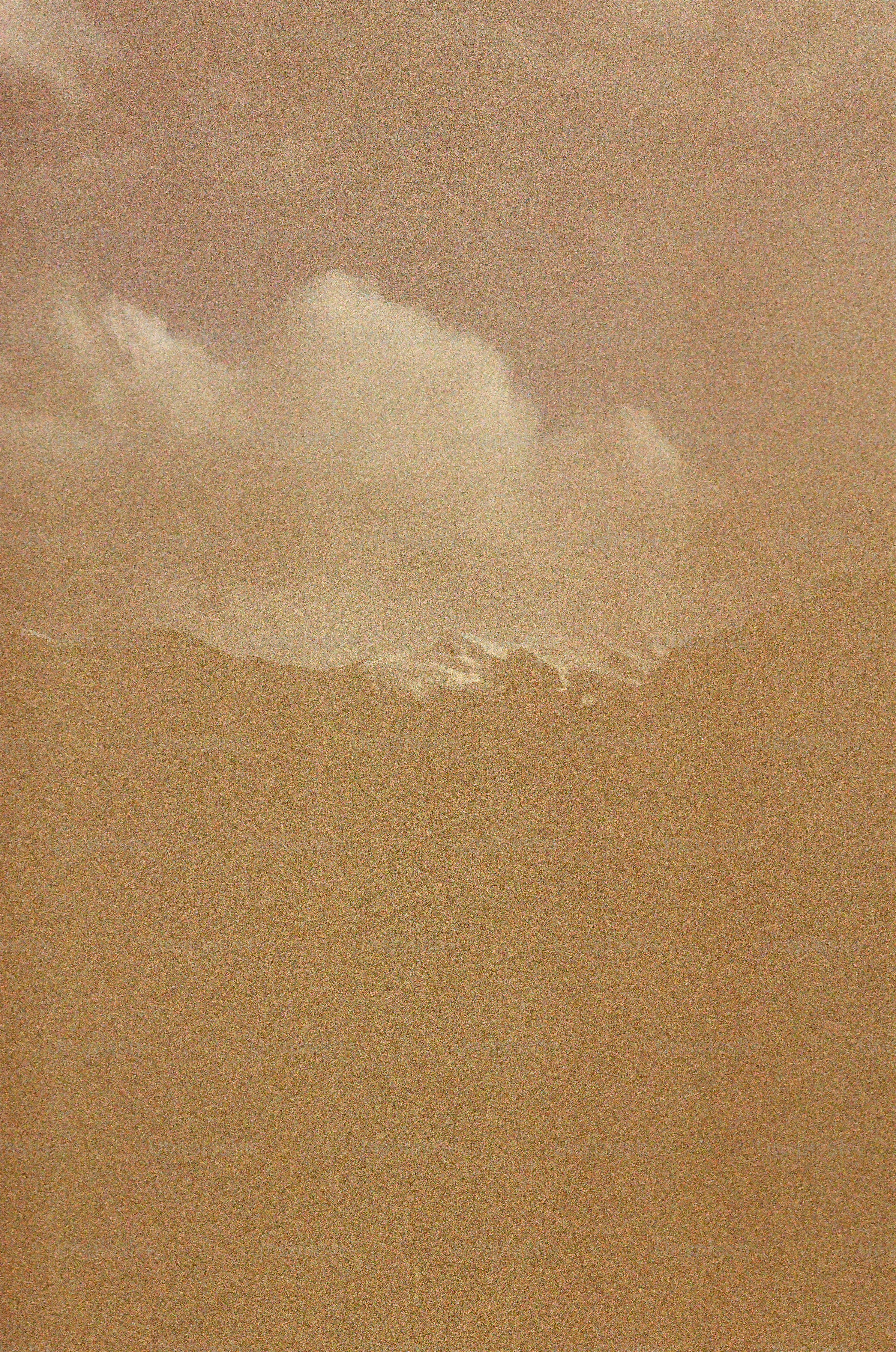 A distant mountain range partially obscured by a thick layer of golden atmospheric haze