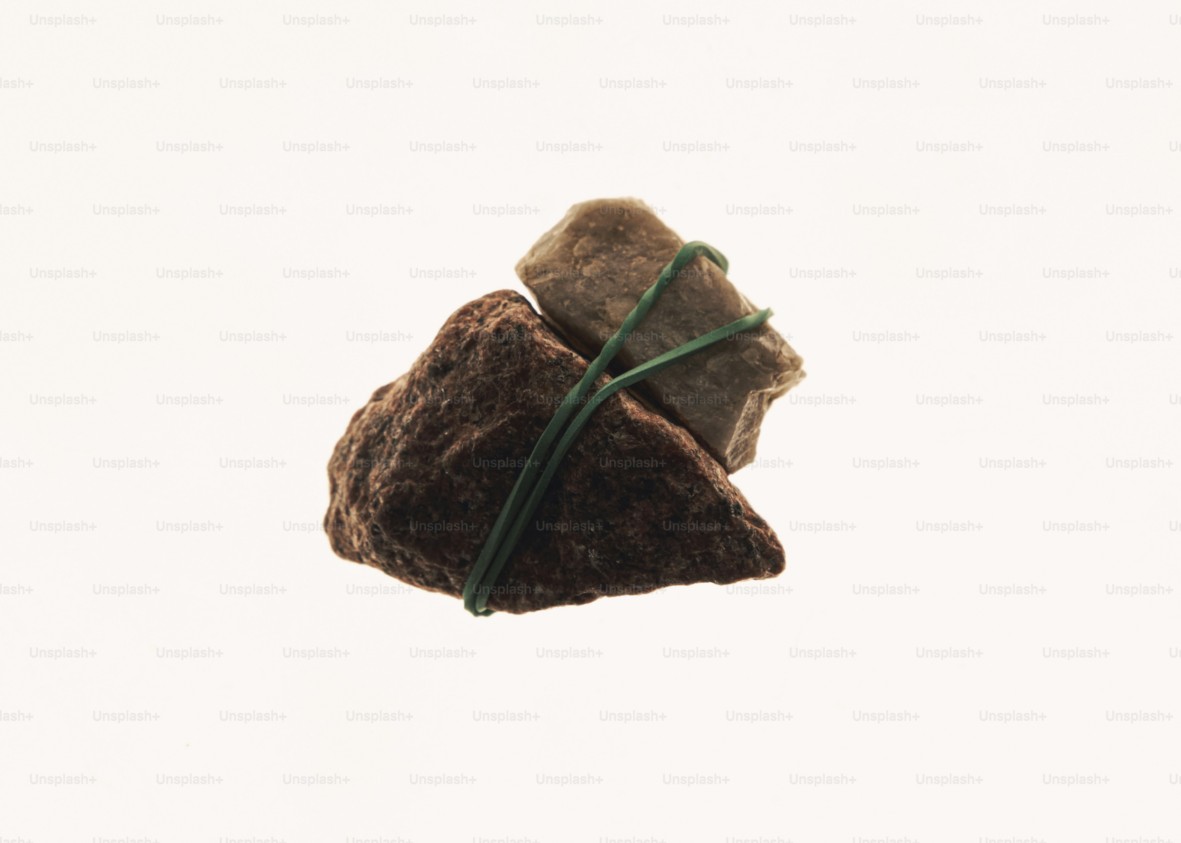 Two rough stones bound together by a thin green wire against a white background