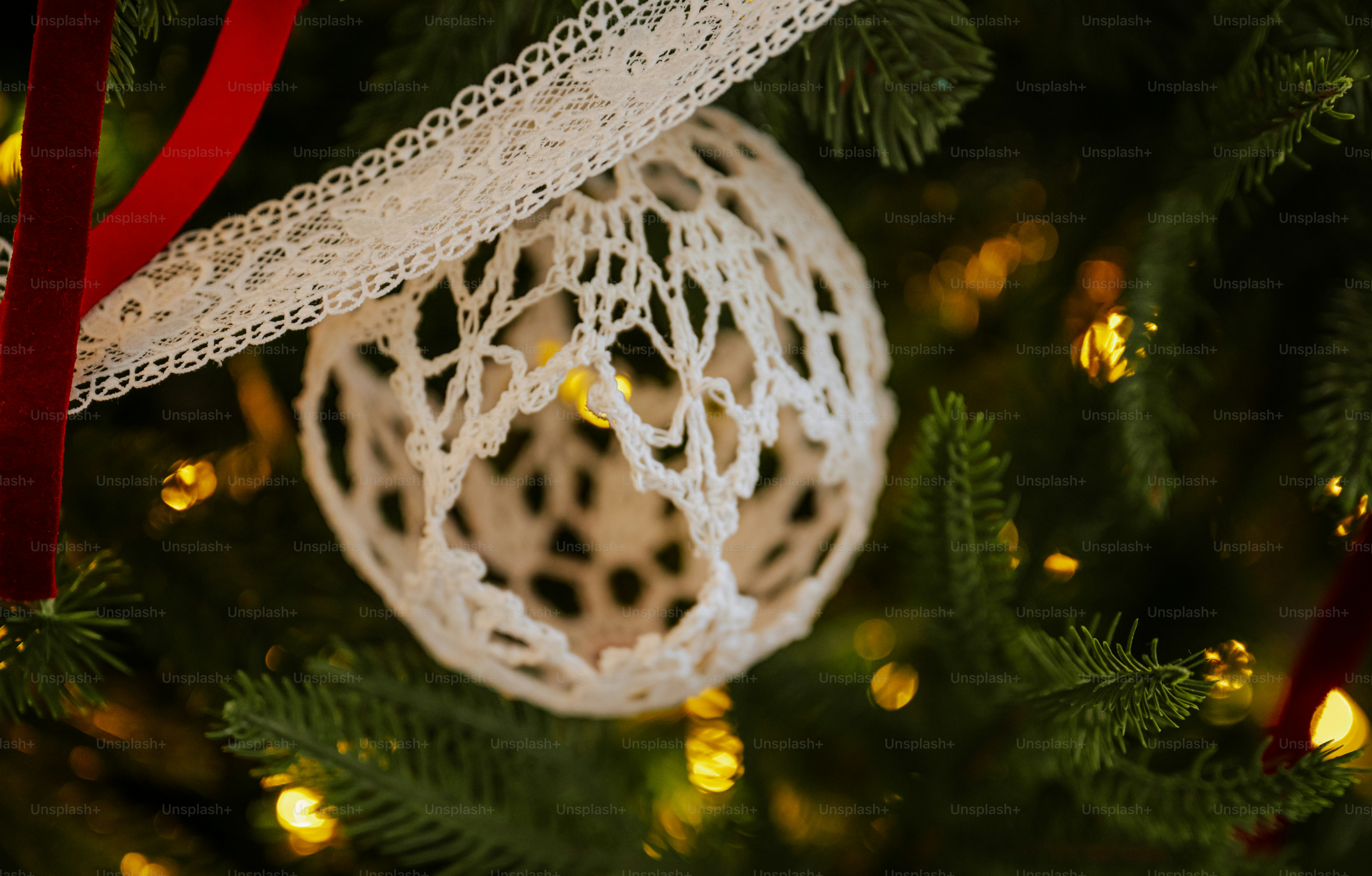 A white crocheted ornament hanging on a Christmas tree with warm fairy lights
