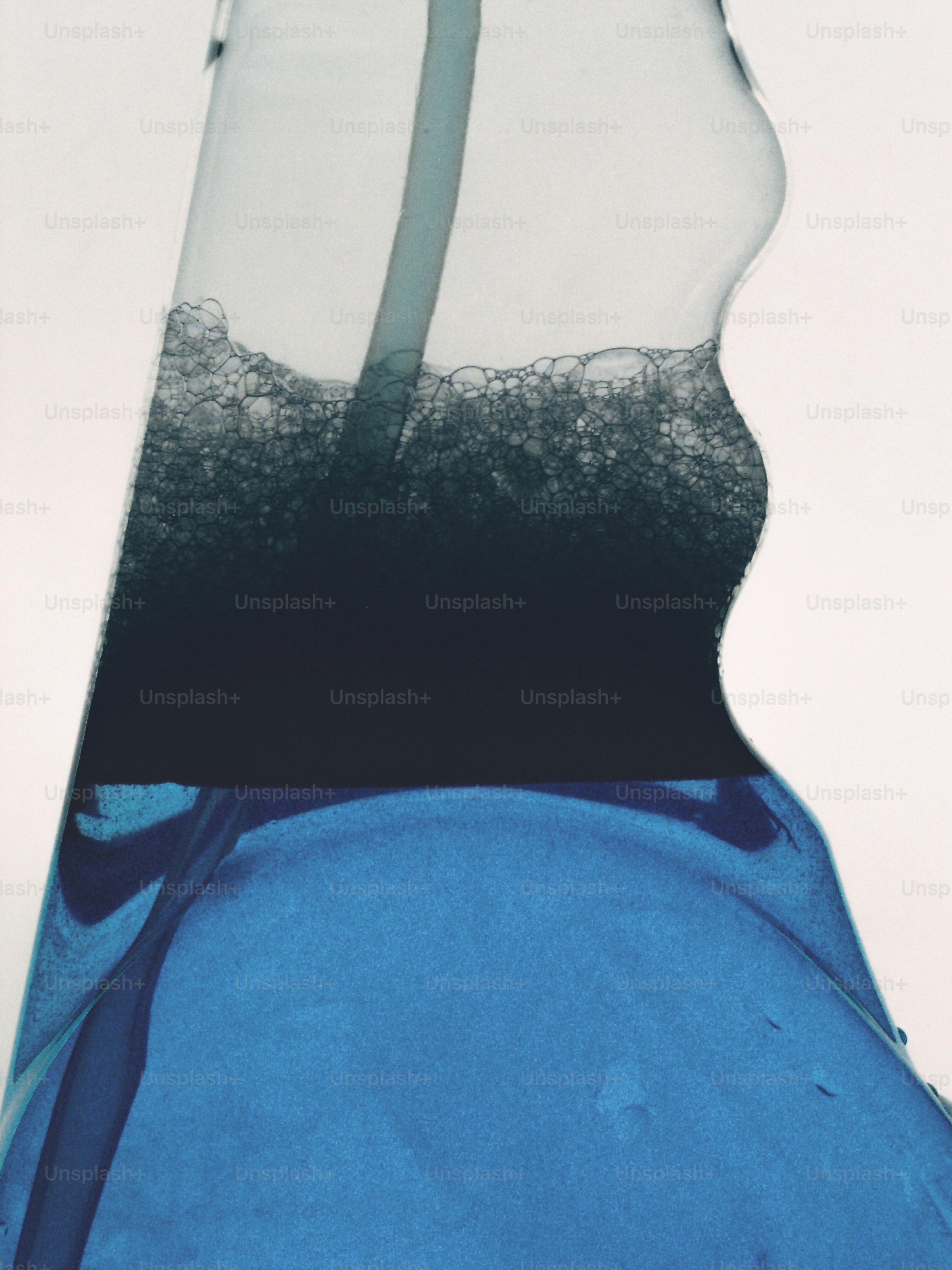 A close-up of blue liquid and dark bubbles inside a glass container