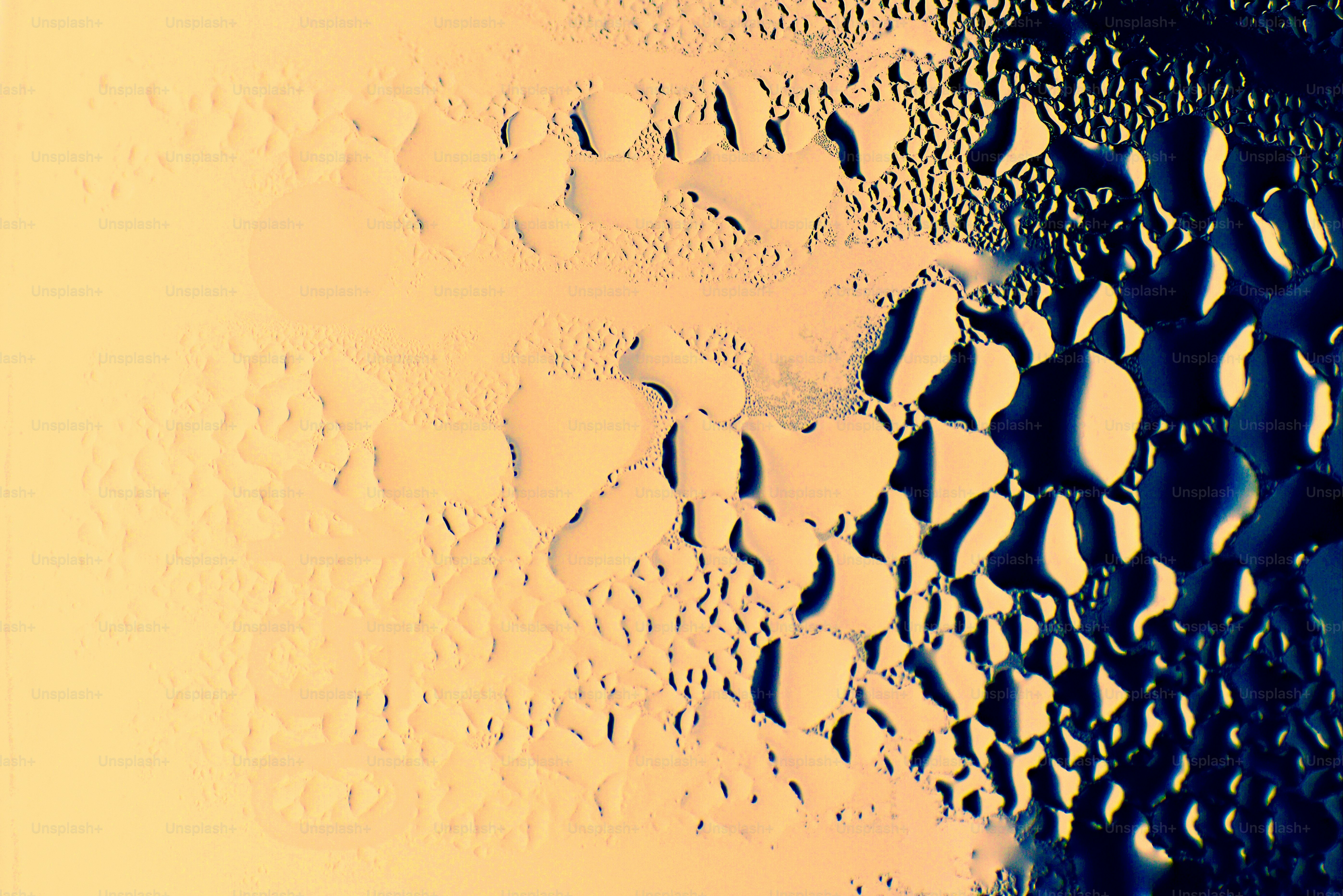 Water droplets on a glass surface transitioning from a warm yellow to a deep blue