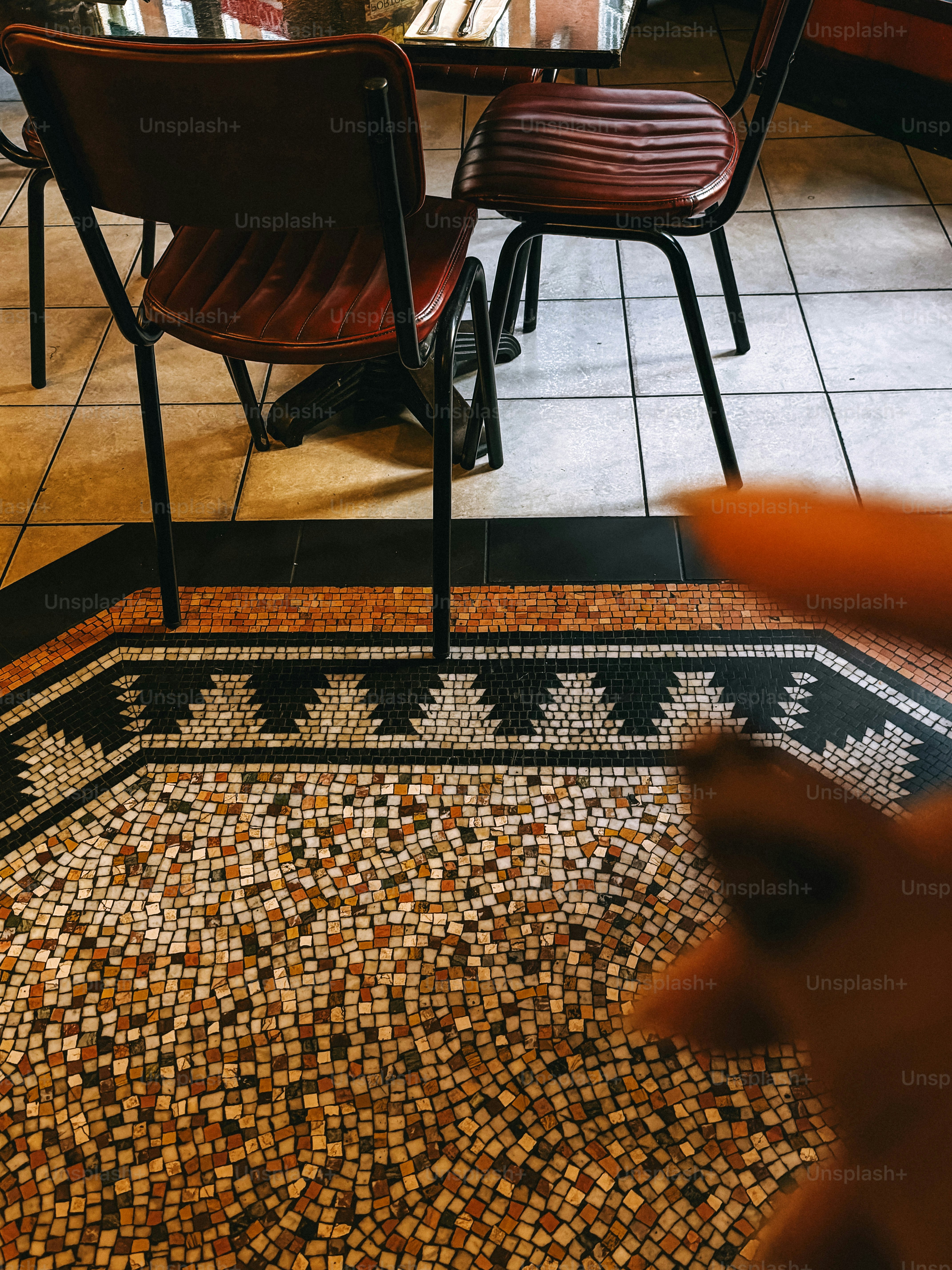Two red chairs at a table on a patterned mosaic tile floor