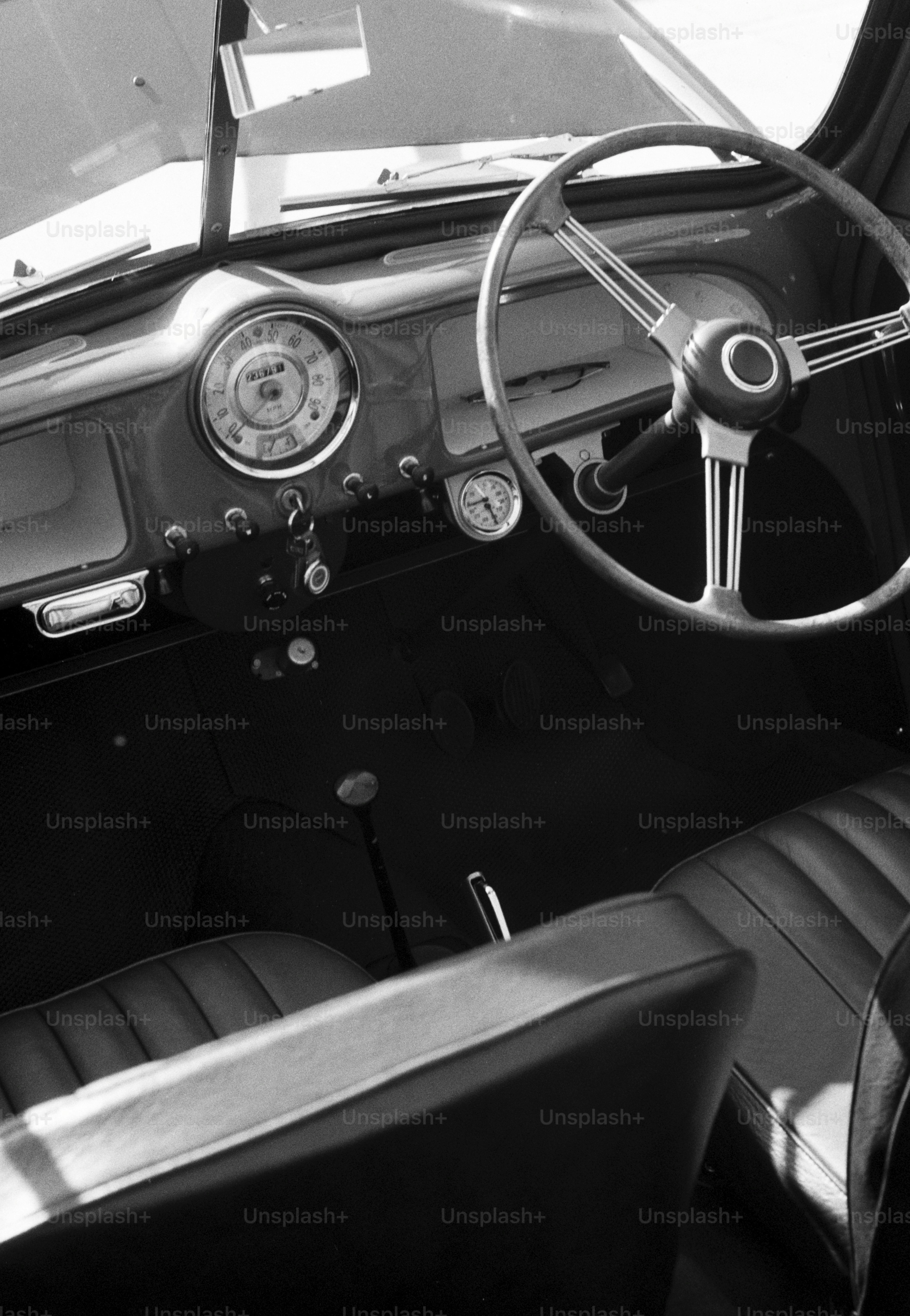 The interior of a vintage car with a large steering wheel and round dashboard gauges