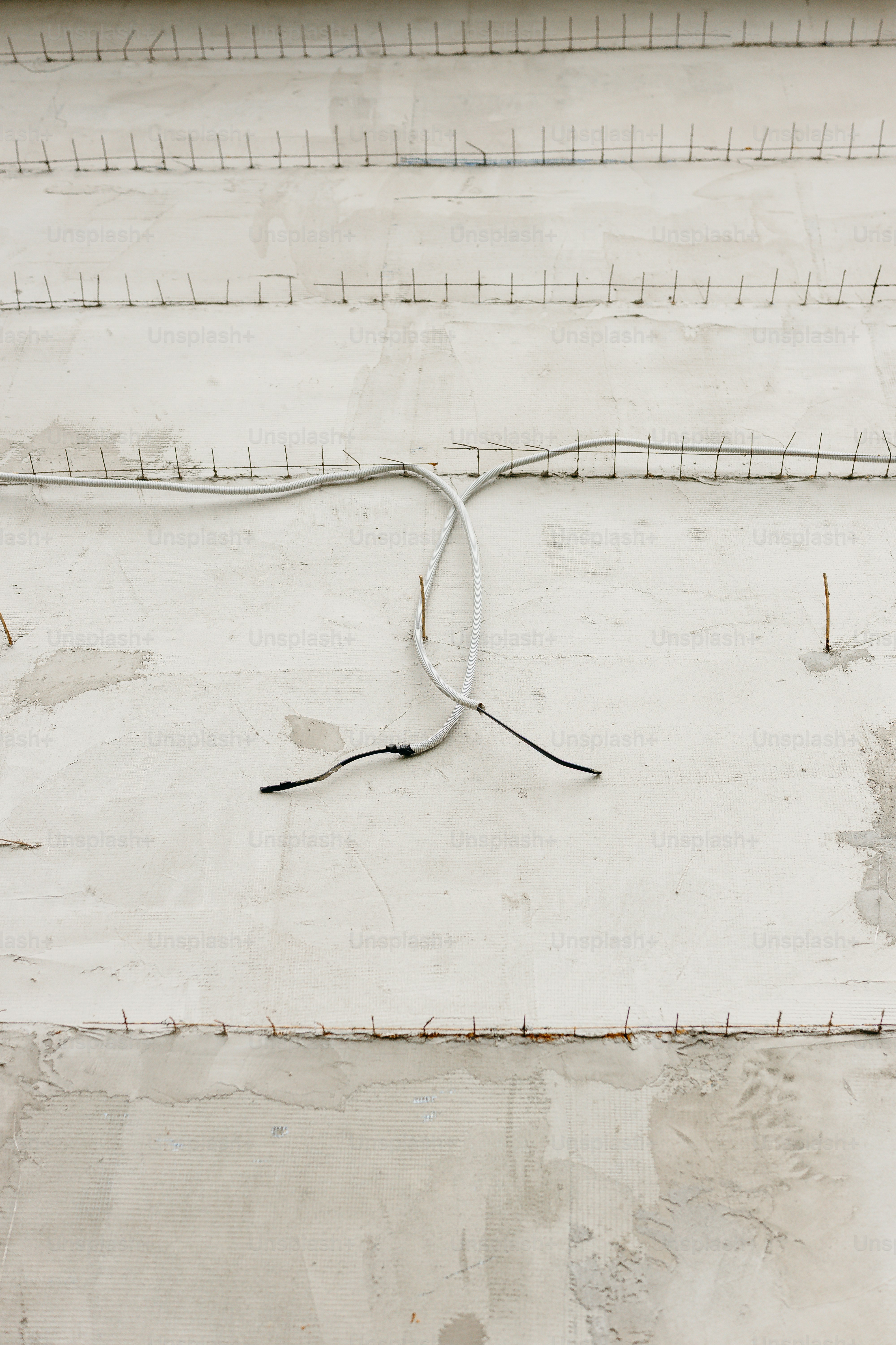 Exposed electrical conduit on concrete wall - Photo on Unsplash+