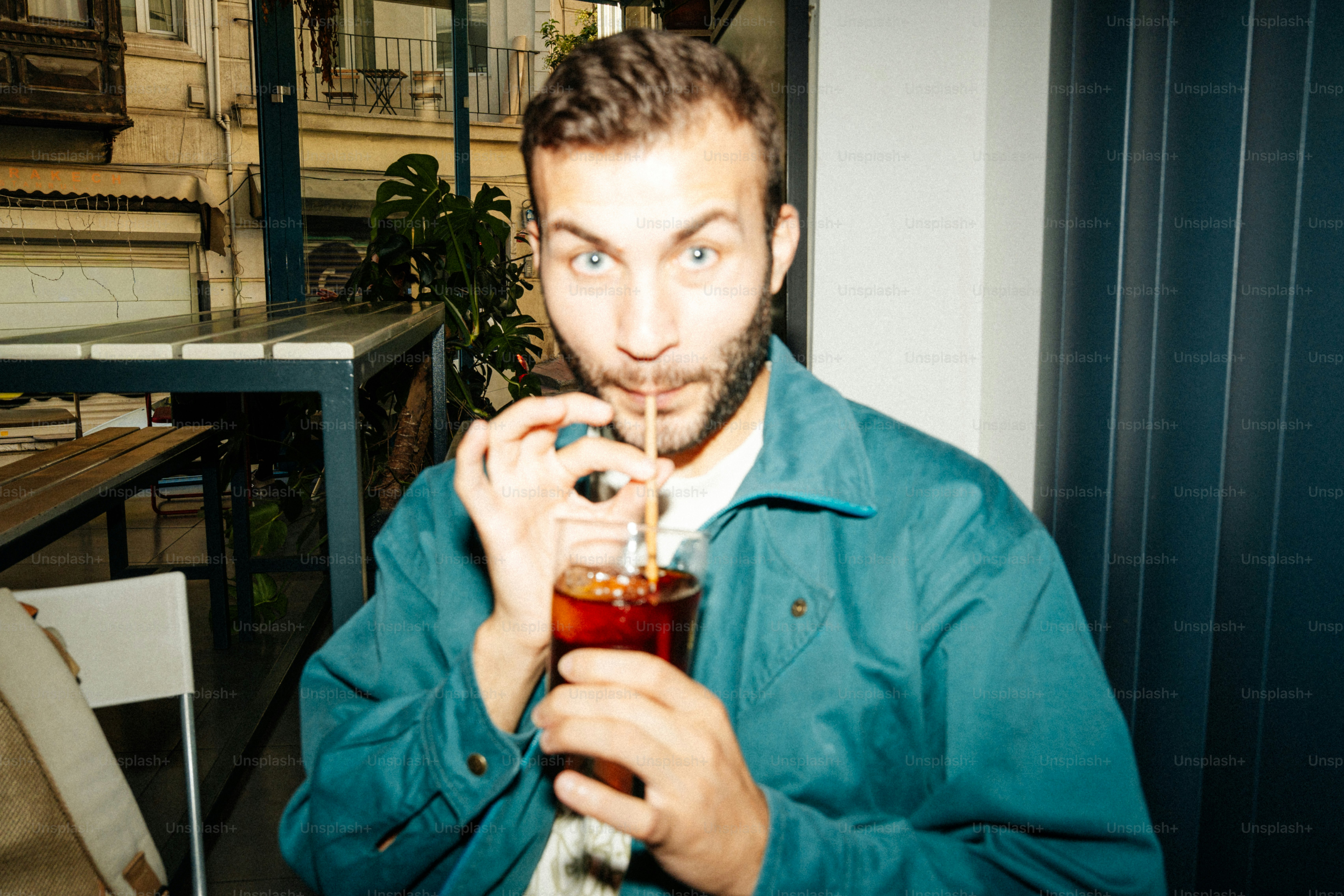 Homme buvant dans un verre avec de la paille - Photo sur Unsplash+