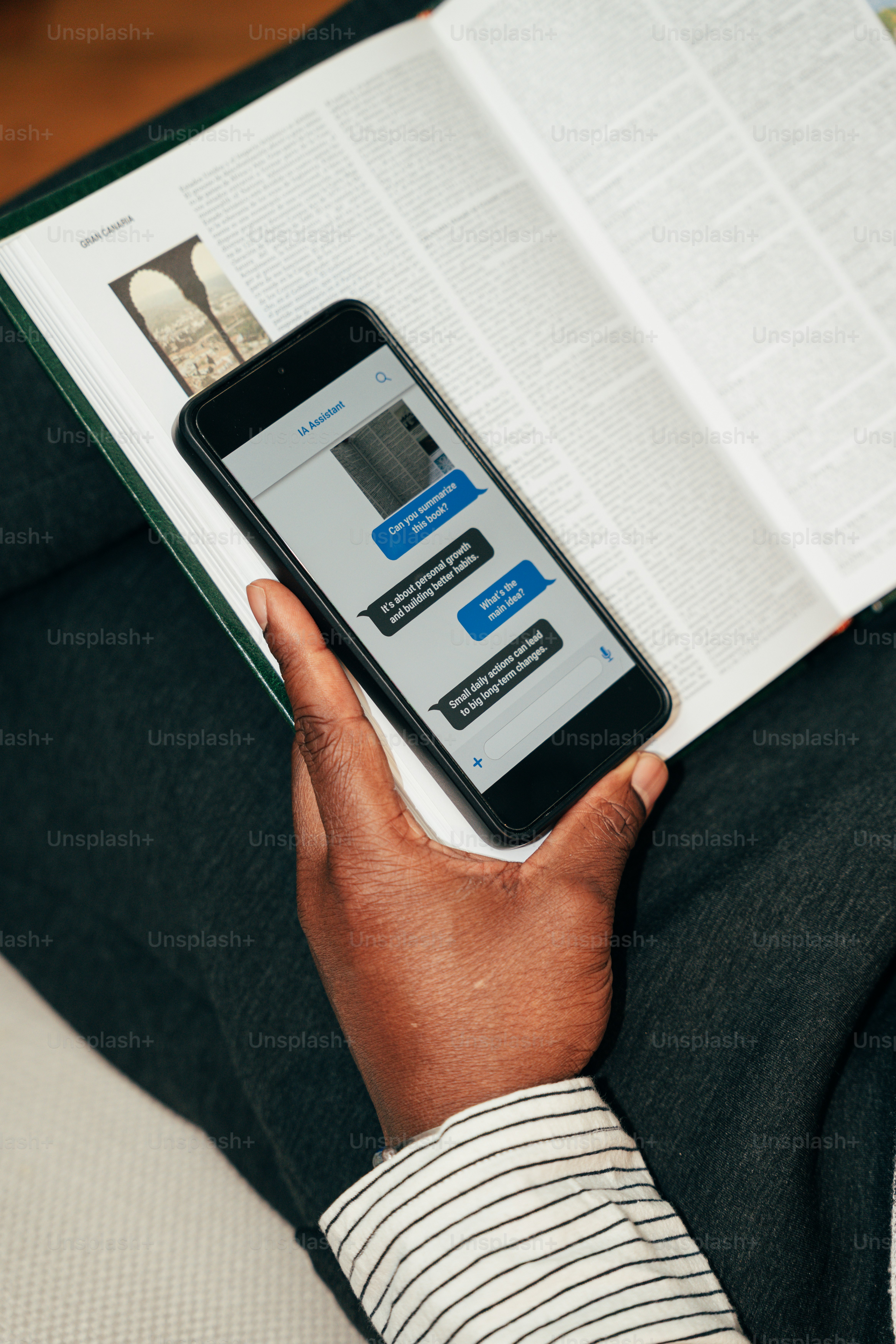 Person holding smartphone over open book - Photo on Unsplash+