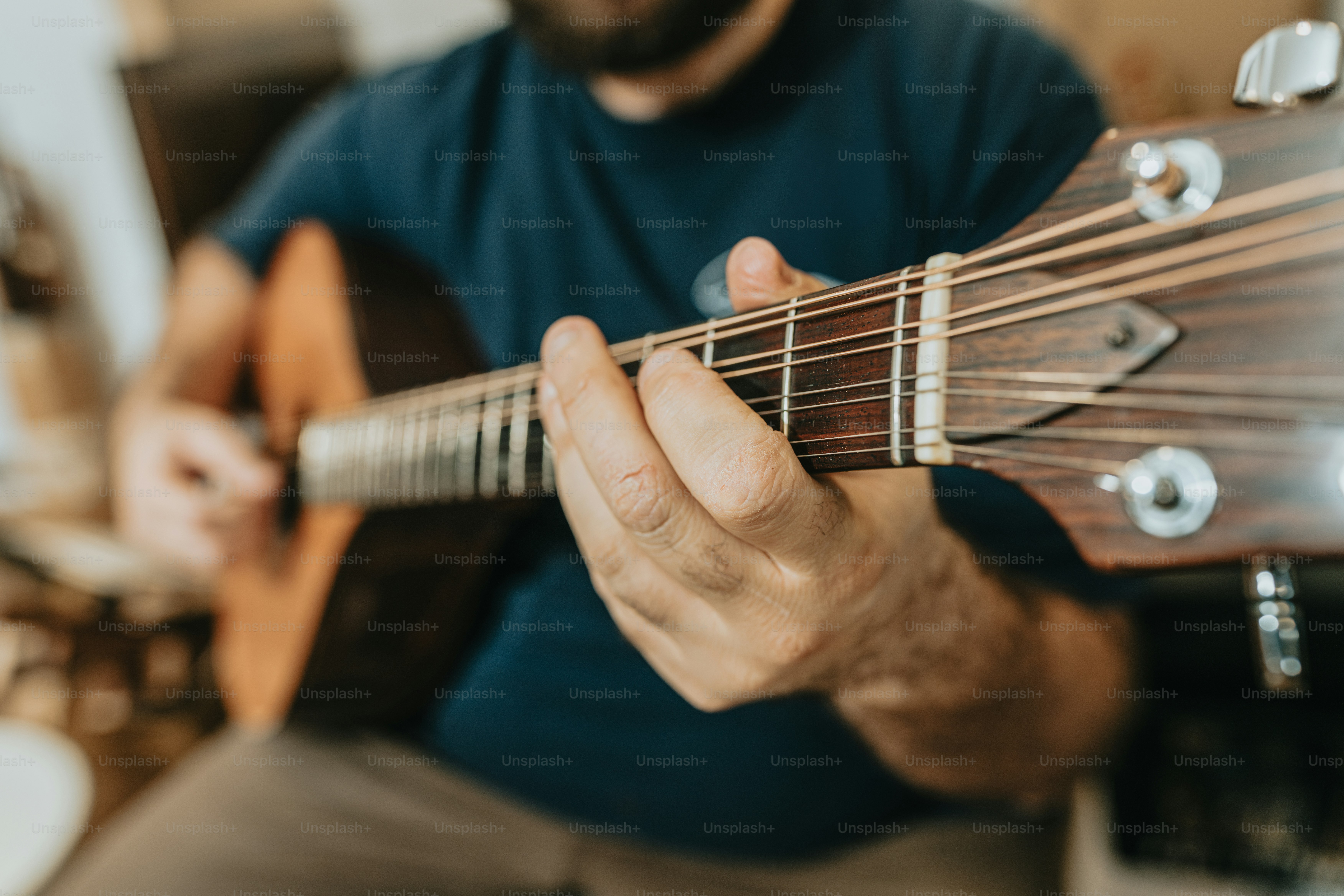Person playing chords on acoustic guitar - Photo on Unsplash+