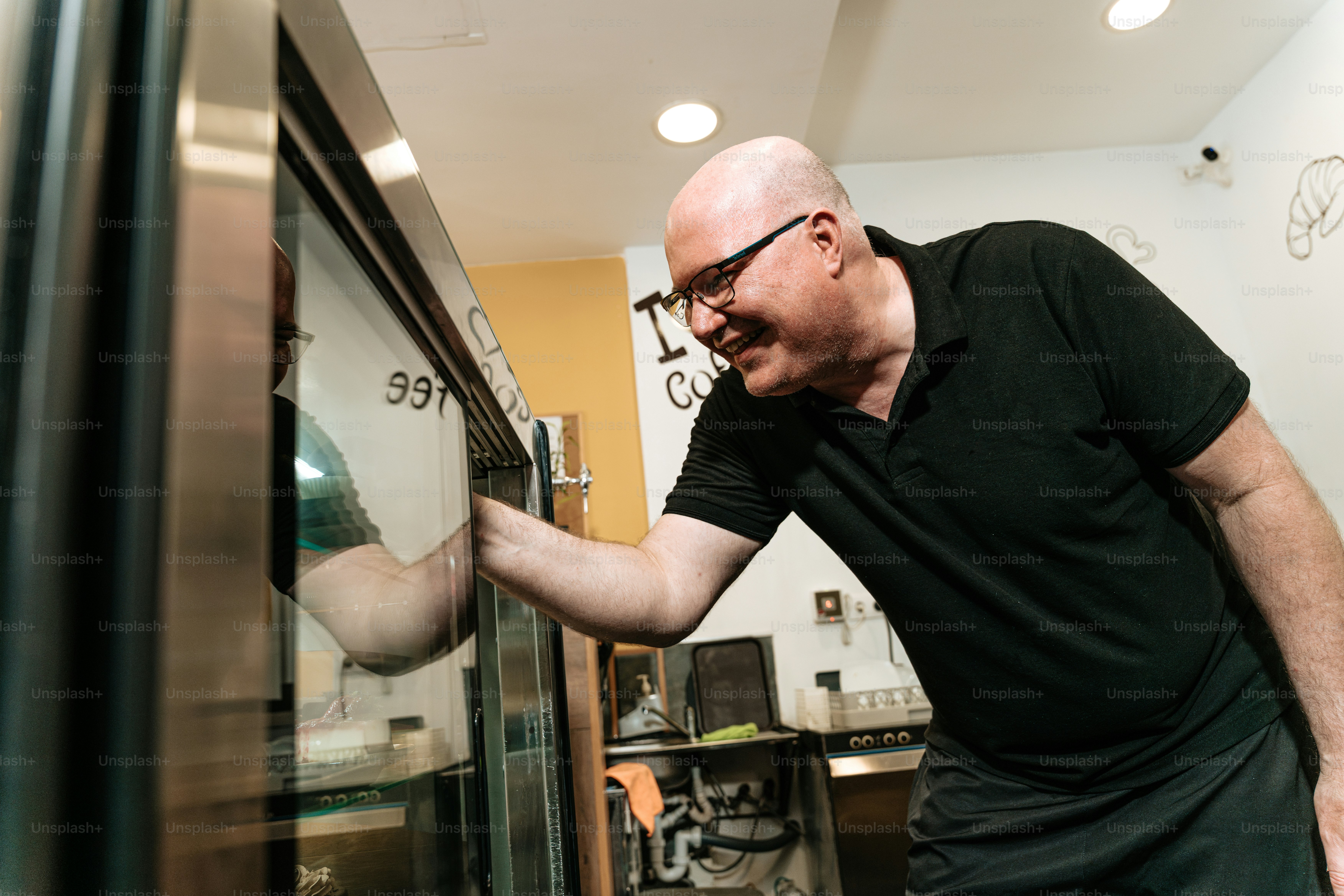 Man opening glass refrigerator in cafe - Photo on Unsplash+