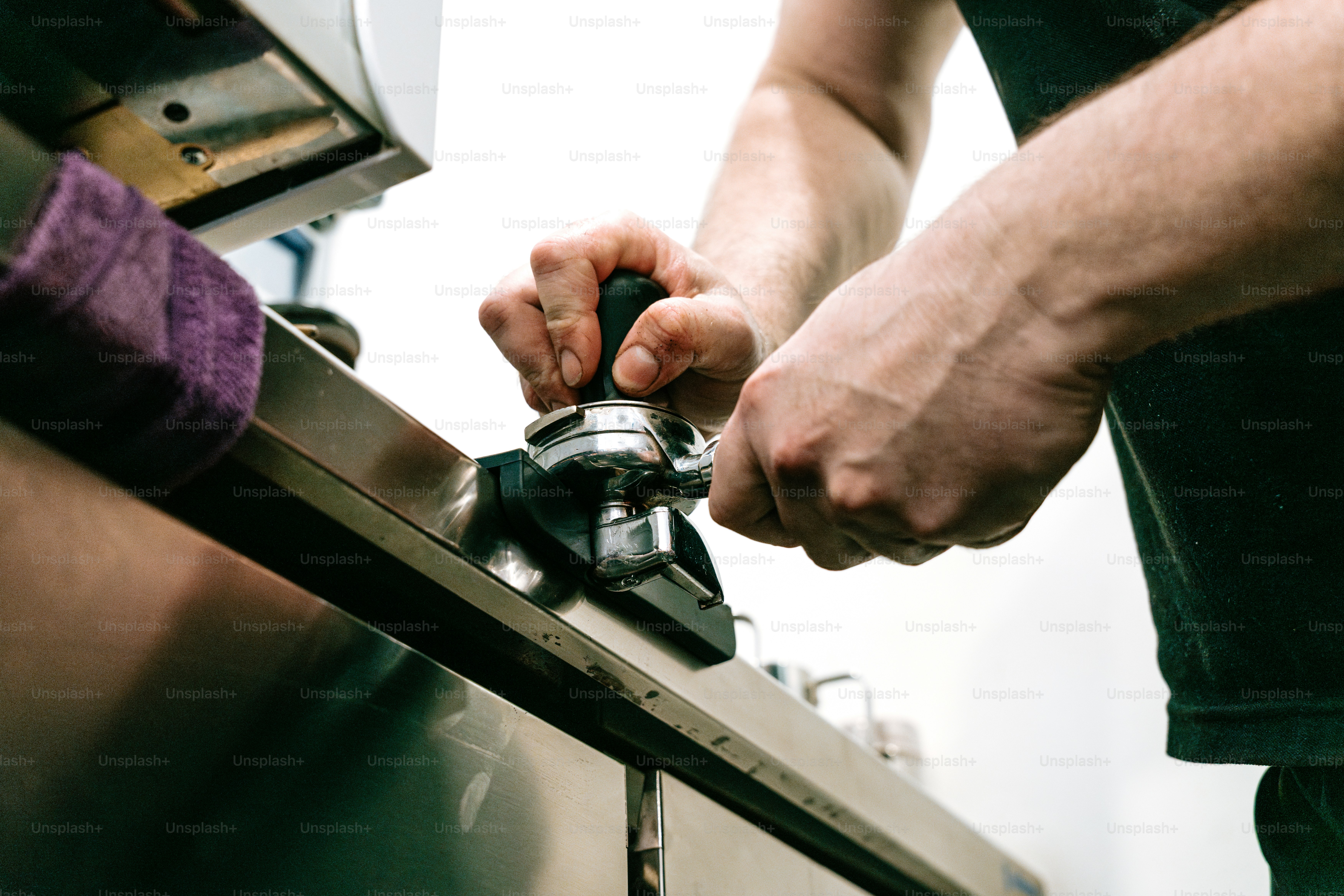 Person tamping coffee in espresso machine - Photo on Unsplash+