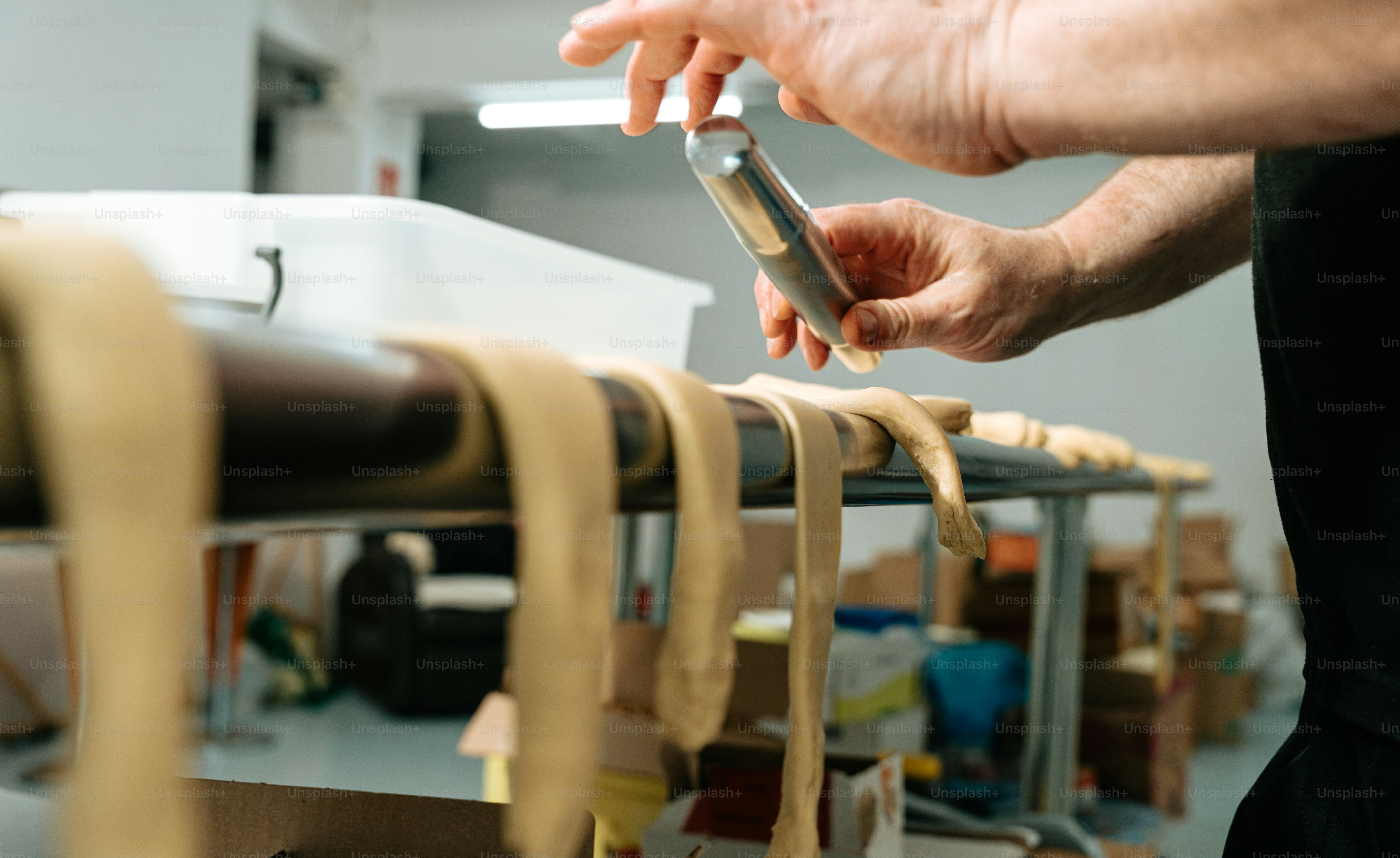 Man shaping dough on metal table - Photo on Unsplash+
