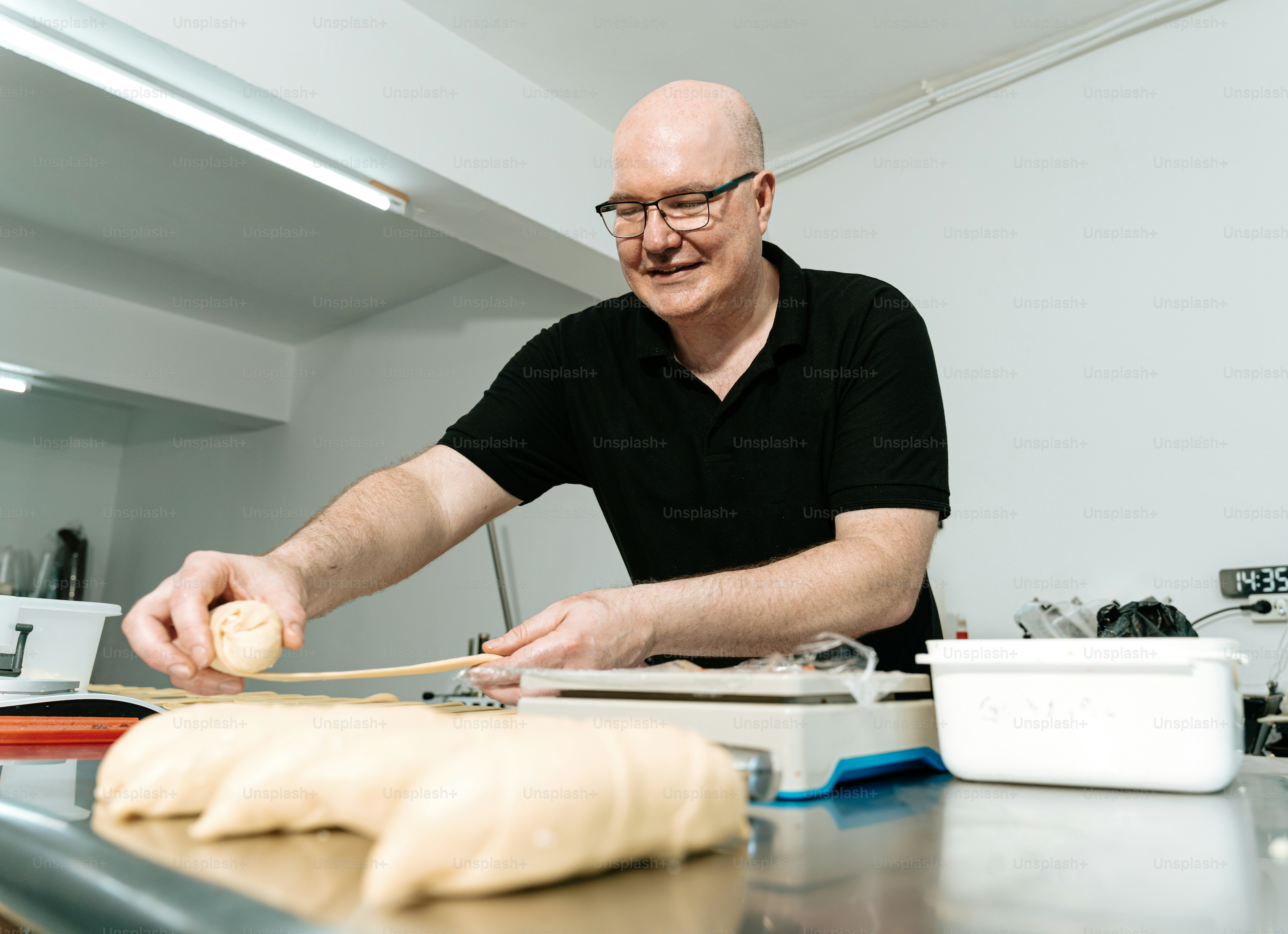 Man shaping dough on metal table - Photo on Unsplash+