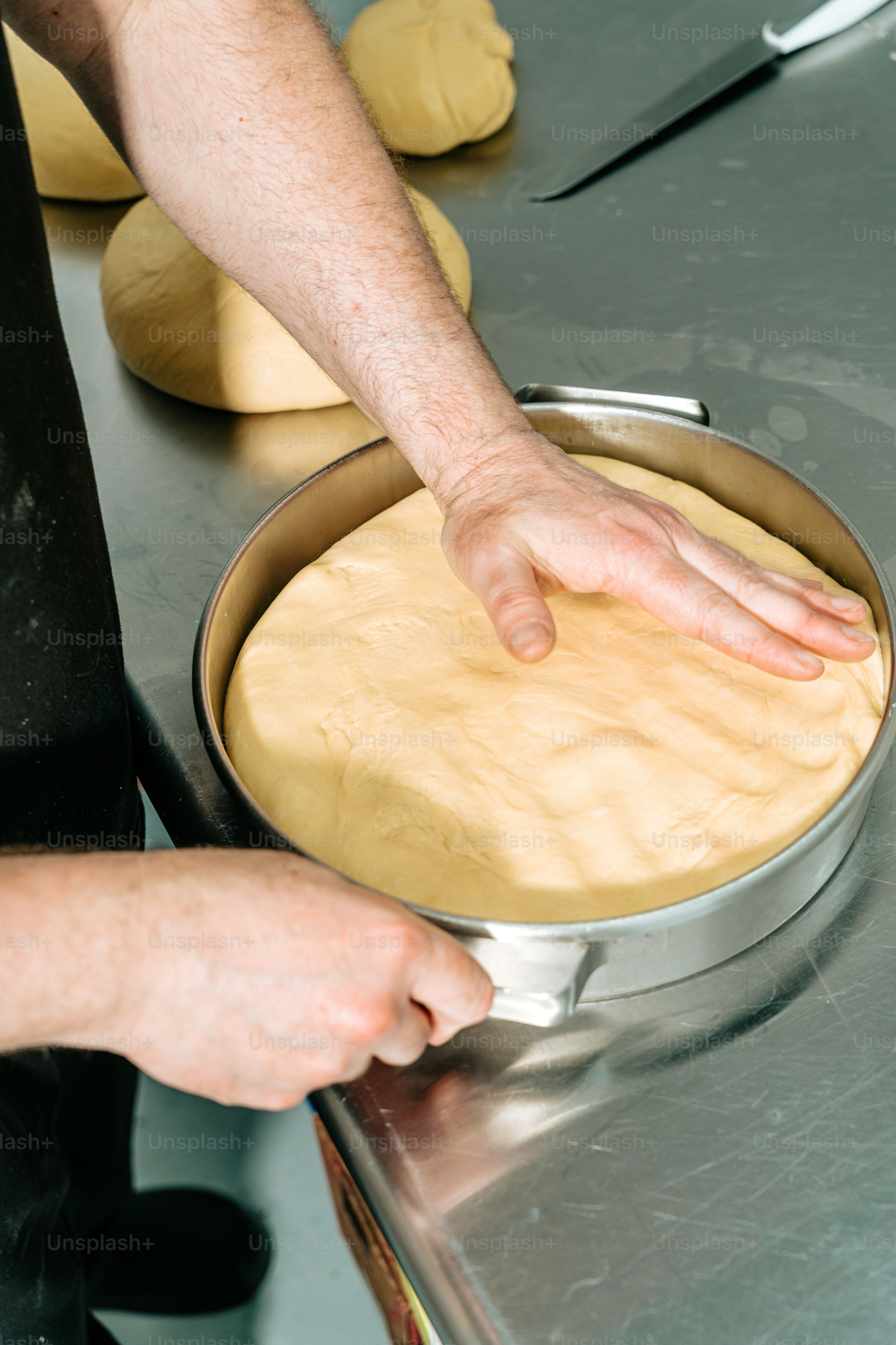 Person pressing dough into baking pan - Photo on Unsplash+