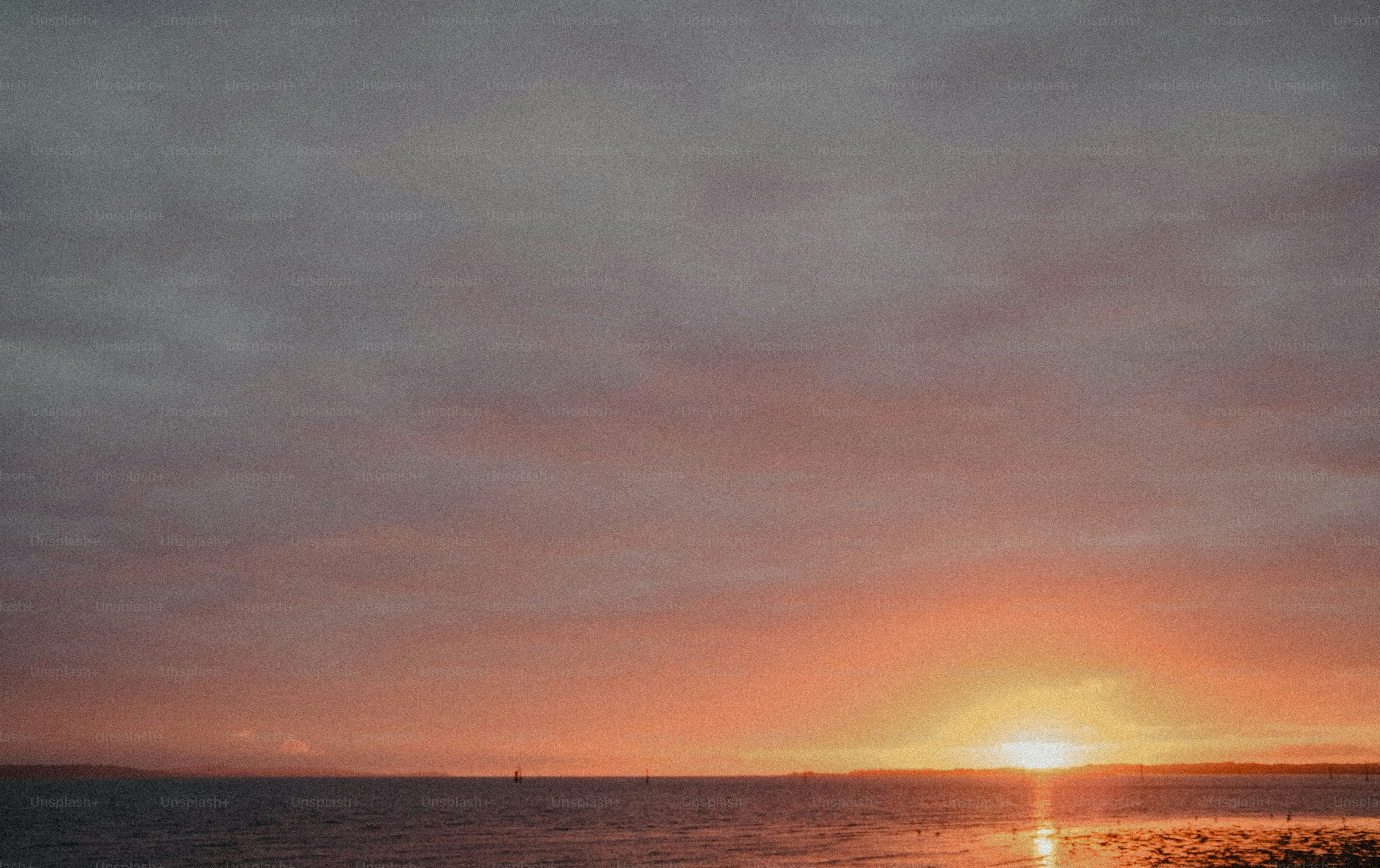 Low sun over a calm sea with a warm orange sky and clouds