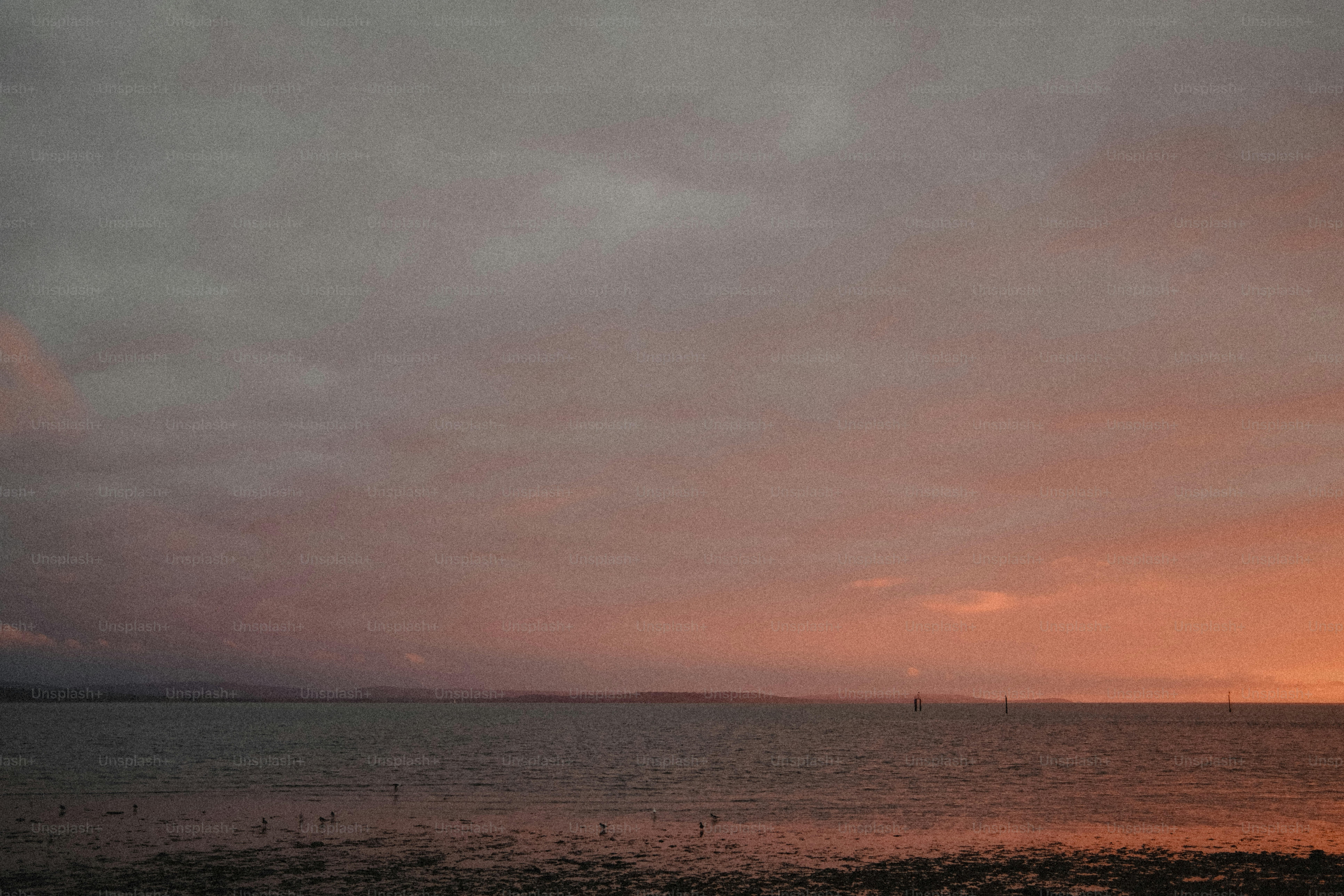 Calm water under a vast sky with warm orange light and dark clouds