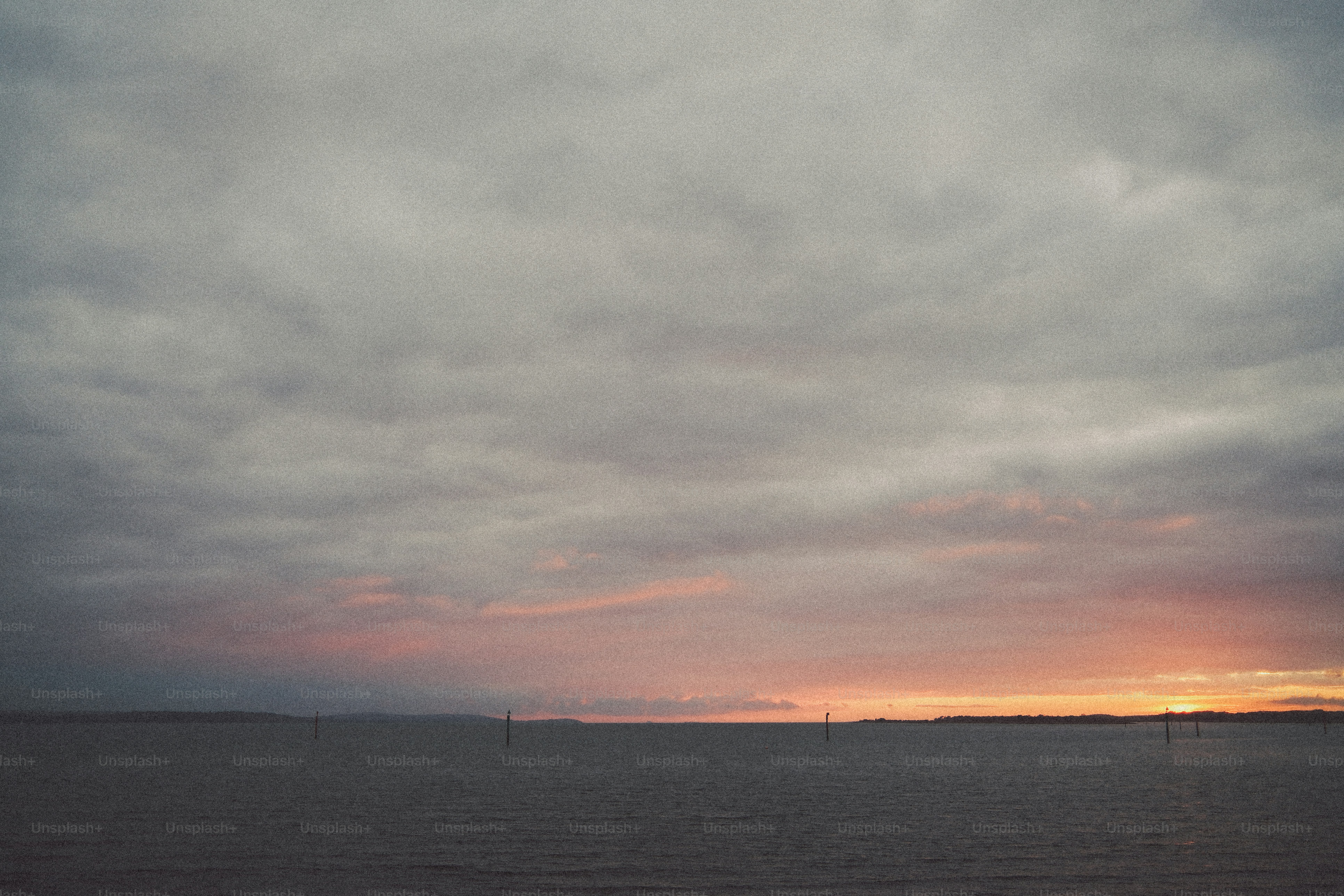 Low sun glowing on the horizon beneath a vast expanse of heavy grey clouds