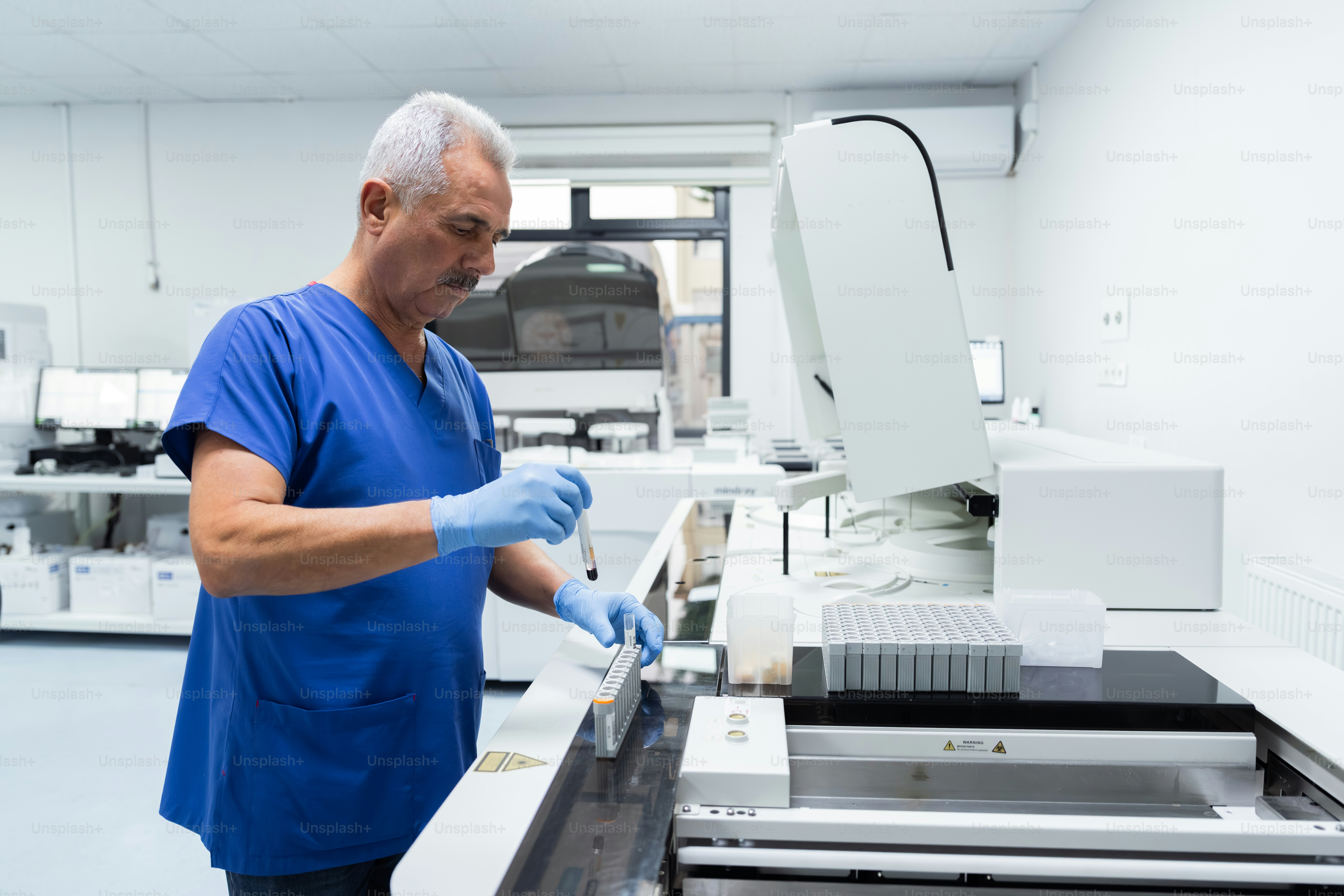 Man in scrubs using laboratory analyzer - Photo on Unsplash+
