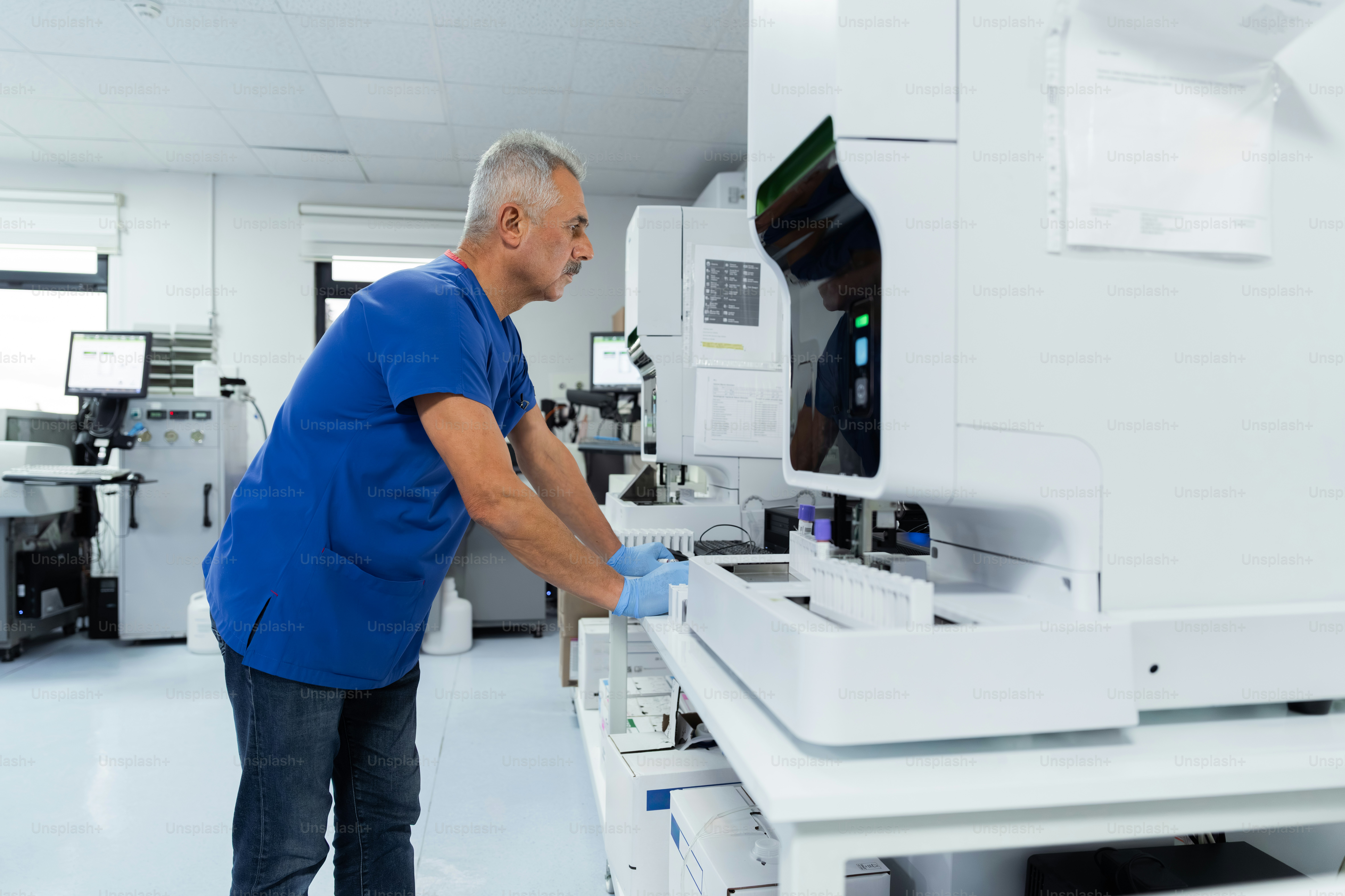 Man in scrubs using laboratory analyzer - Photo on Unsplash+