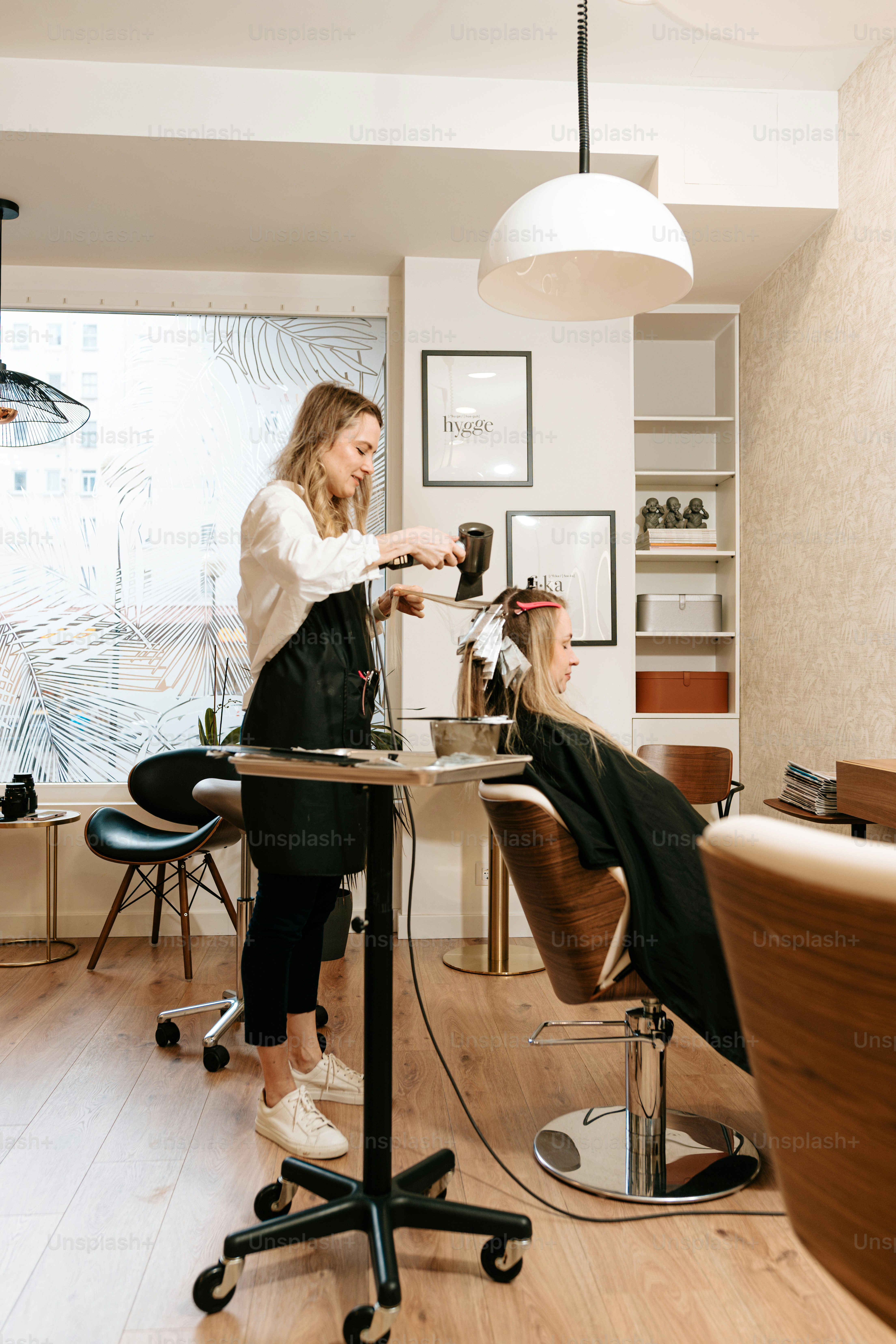 Hairstylist blow drying client hair - Photo on Unsplash+
