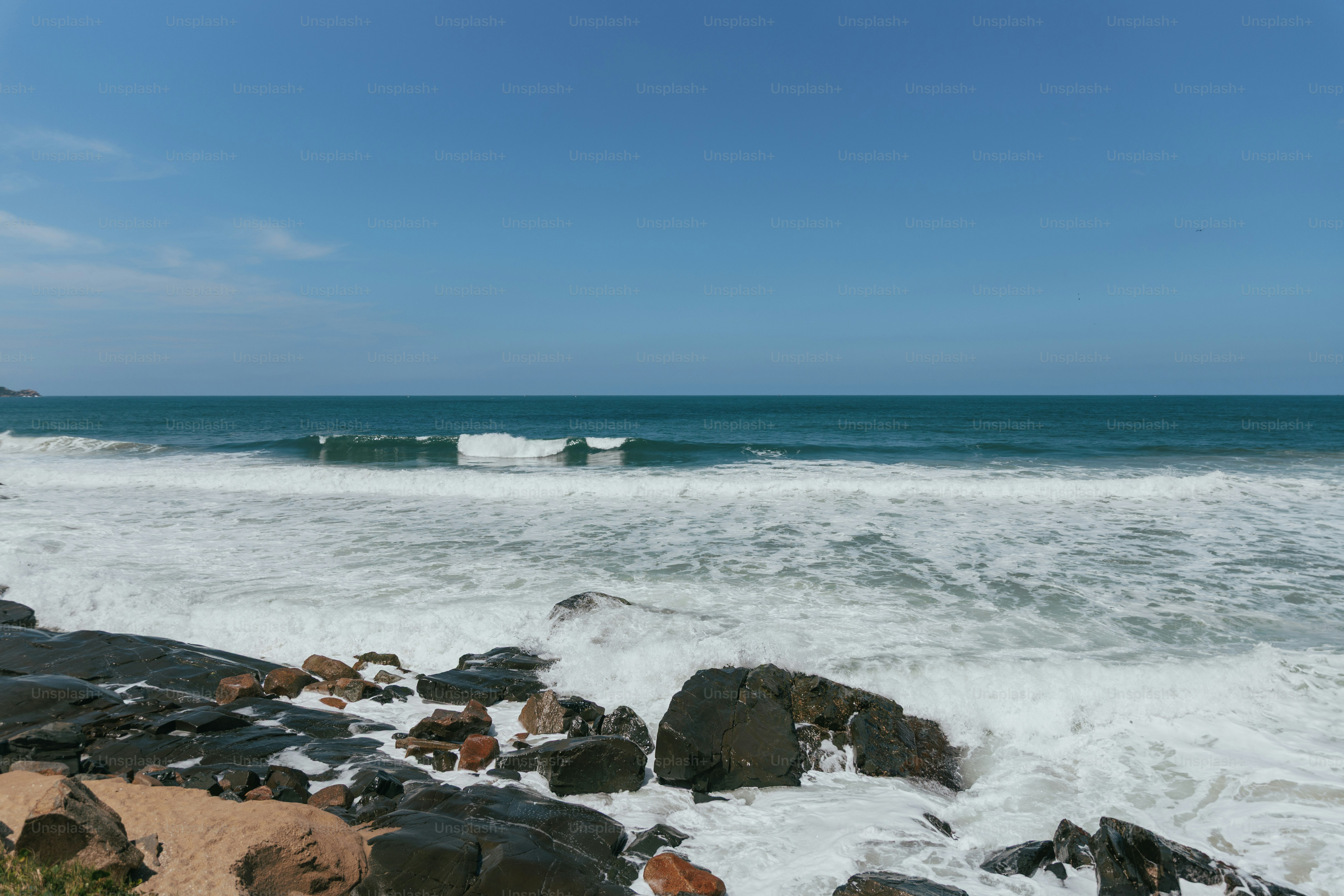 Waves crashing against dark coastal rocks - Photo on Unsplash+