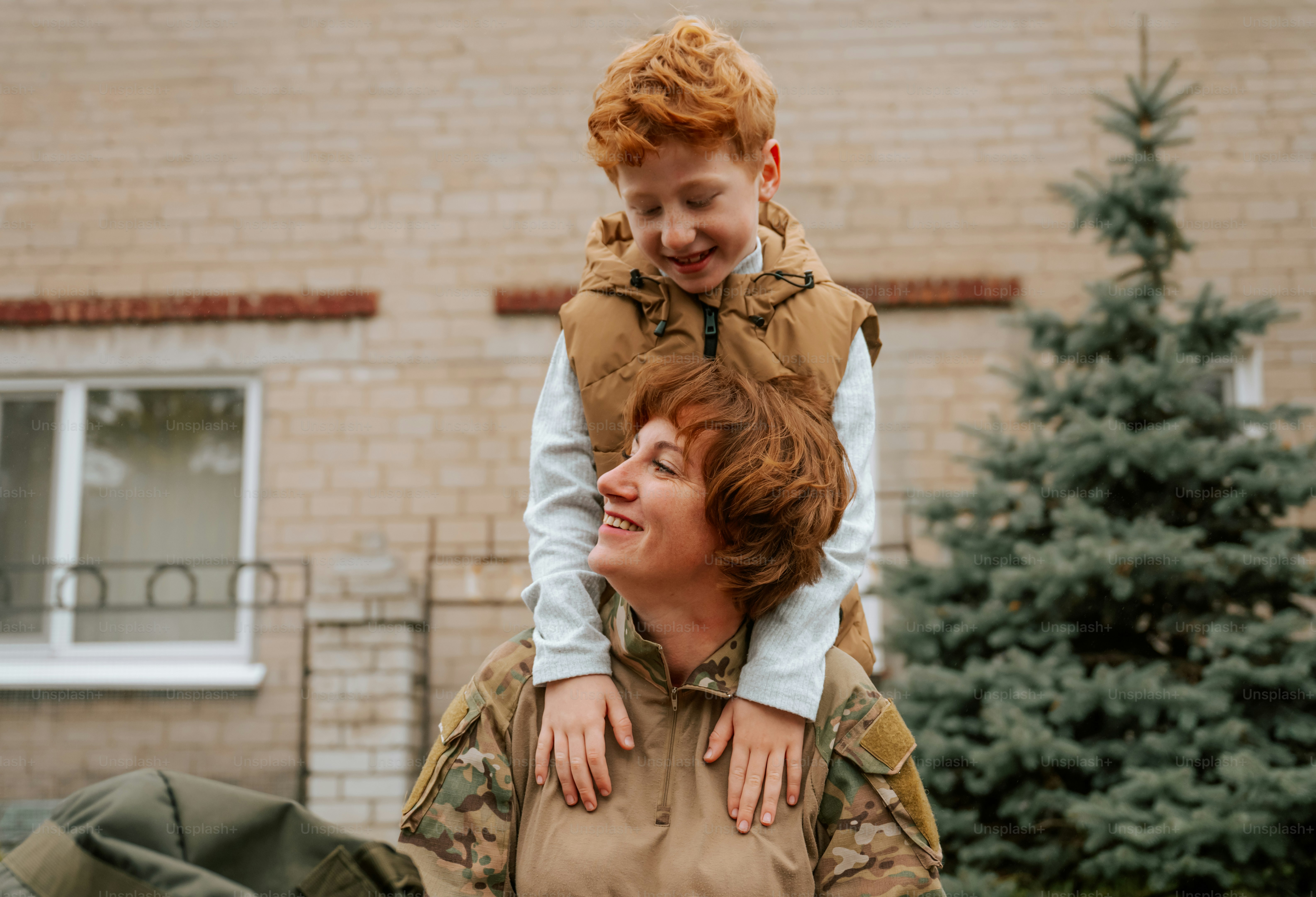 Woman in camouflage uniform holding child - Photo on Unsplash+