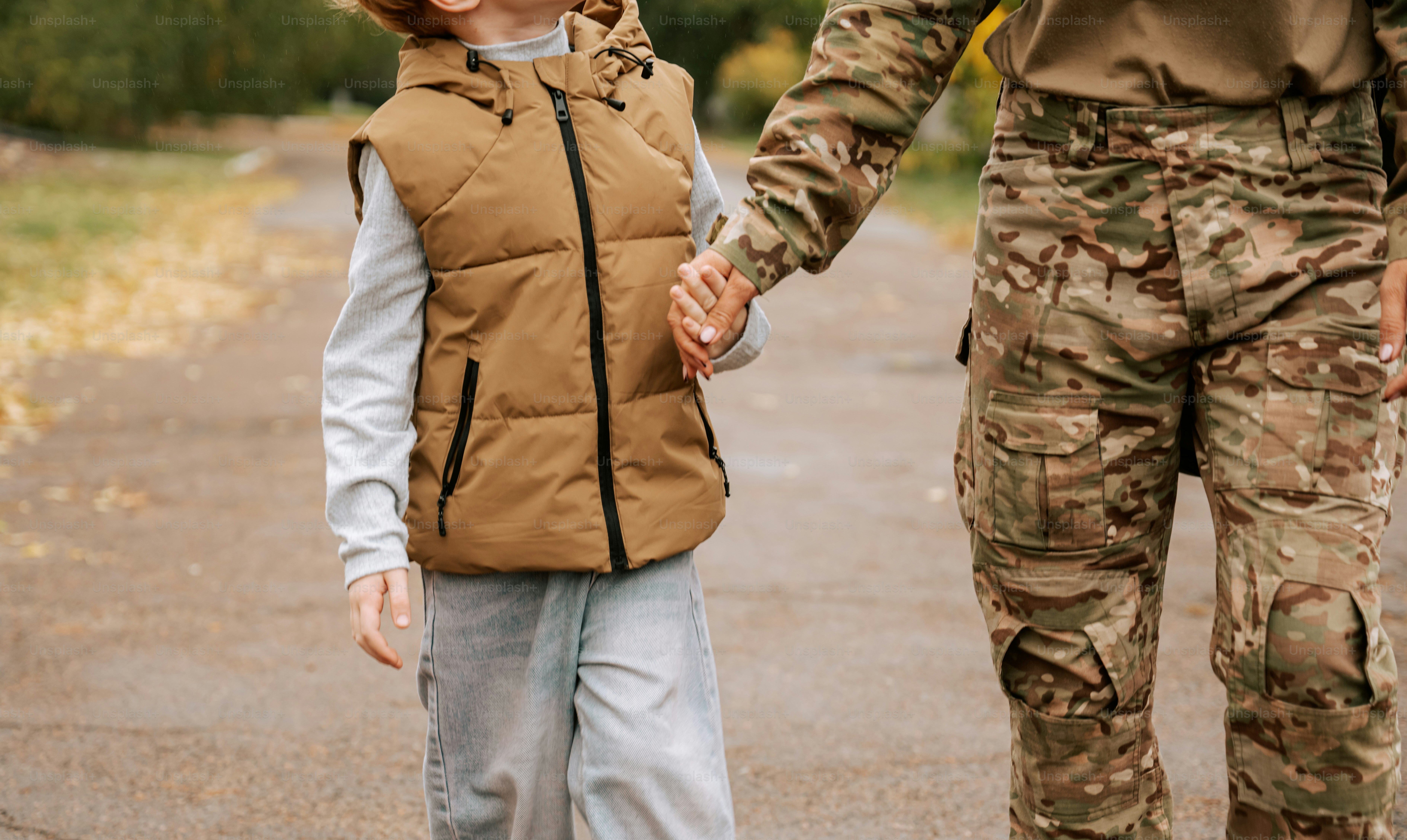 Child holding hands with military adult - Photo on Unsplash+