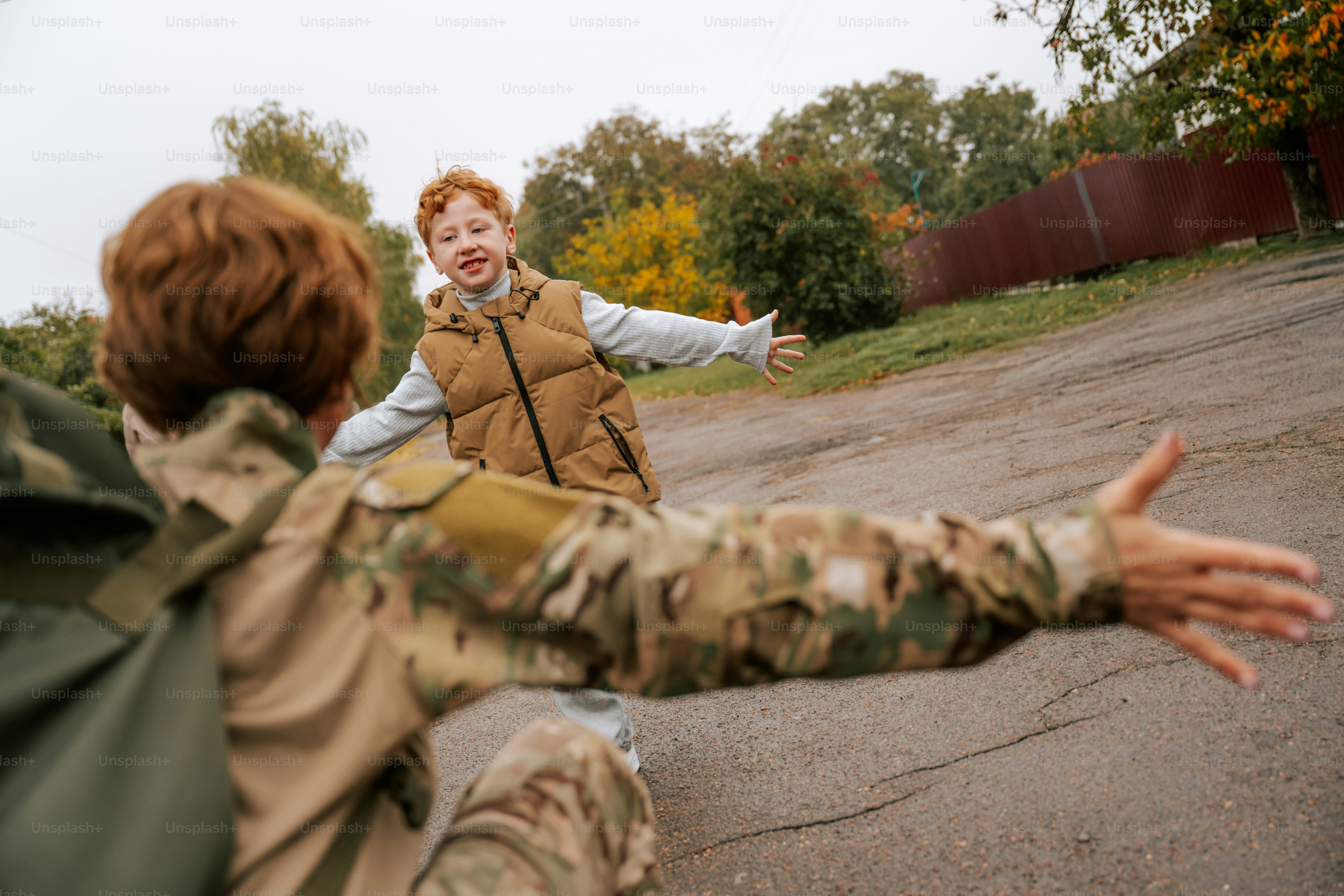 Child running toward adult in camouflage - Photo on Unsplash+
