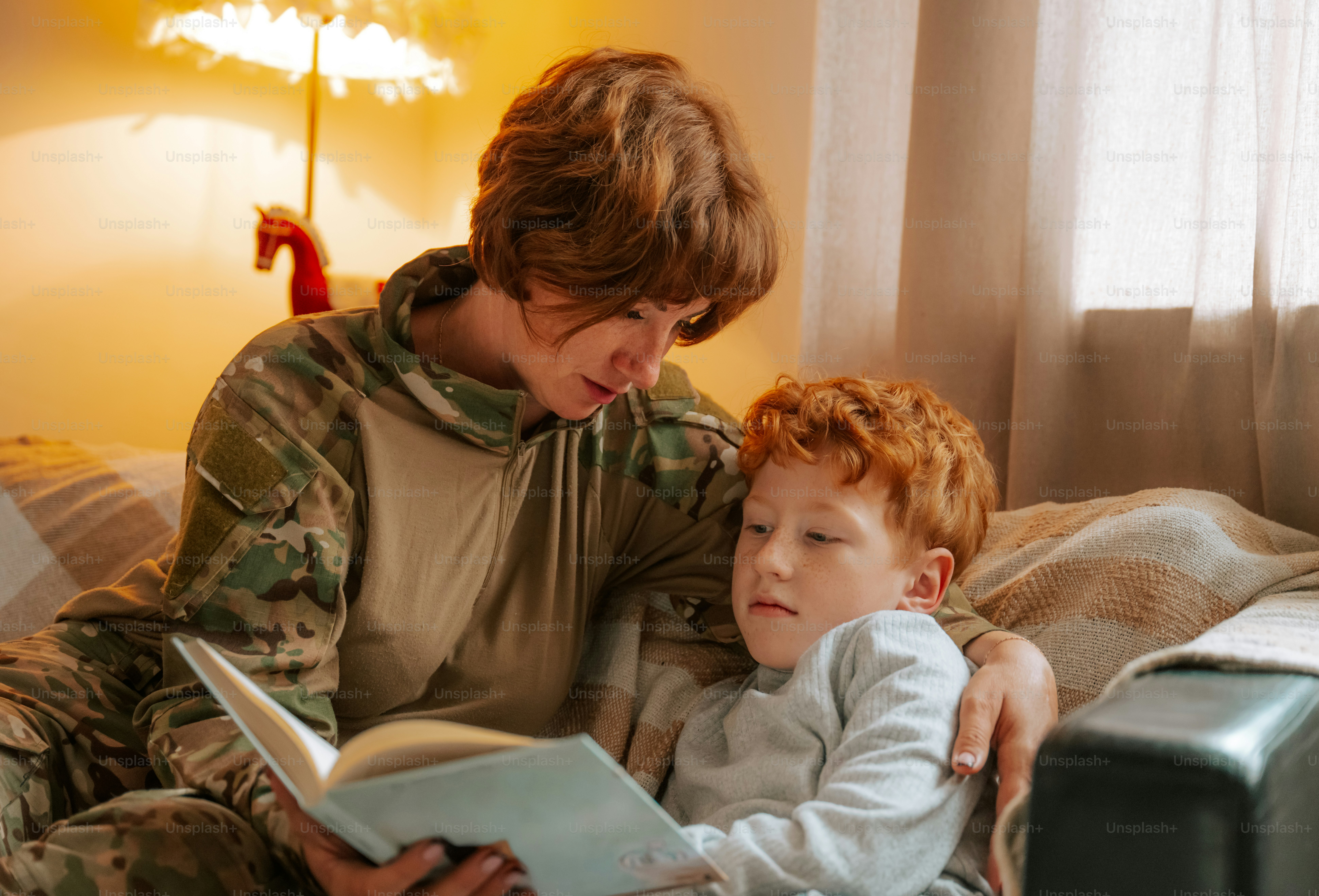 Woman in camouflage reading to child - Photo on Unsplash+