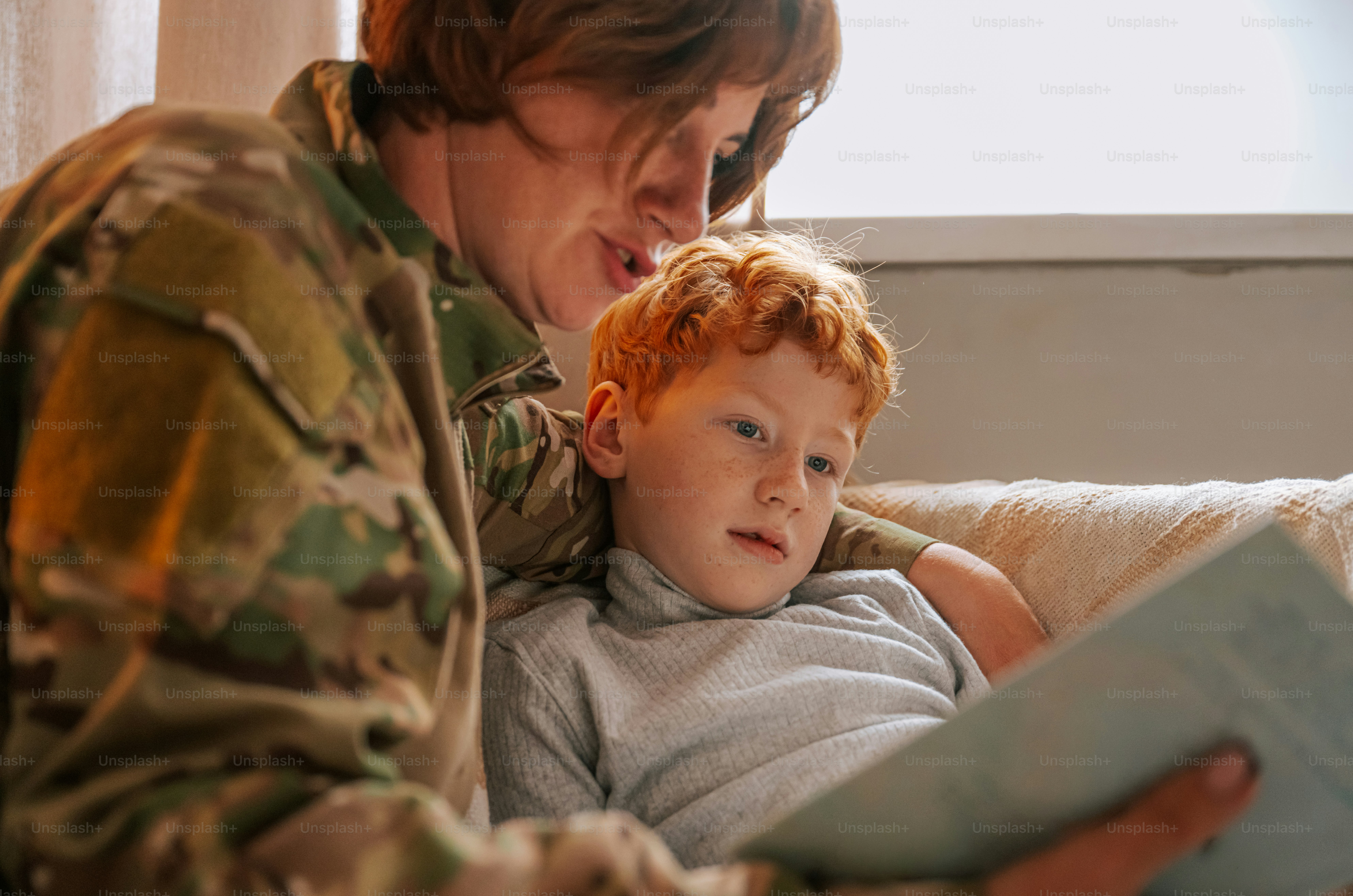 Woman in camouflage reading to child - Photo on Unsplash+