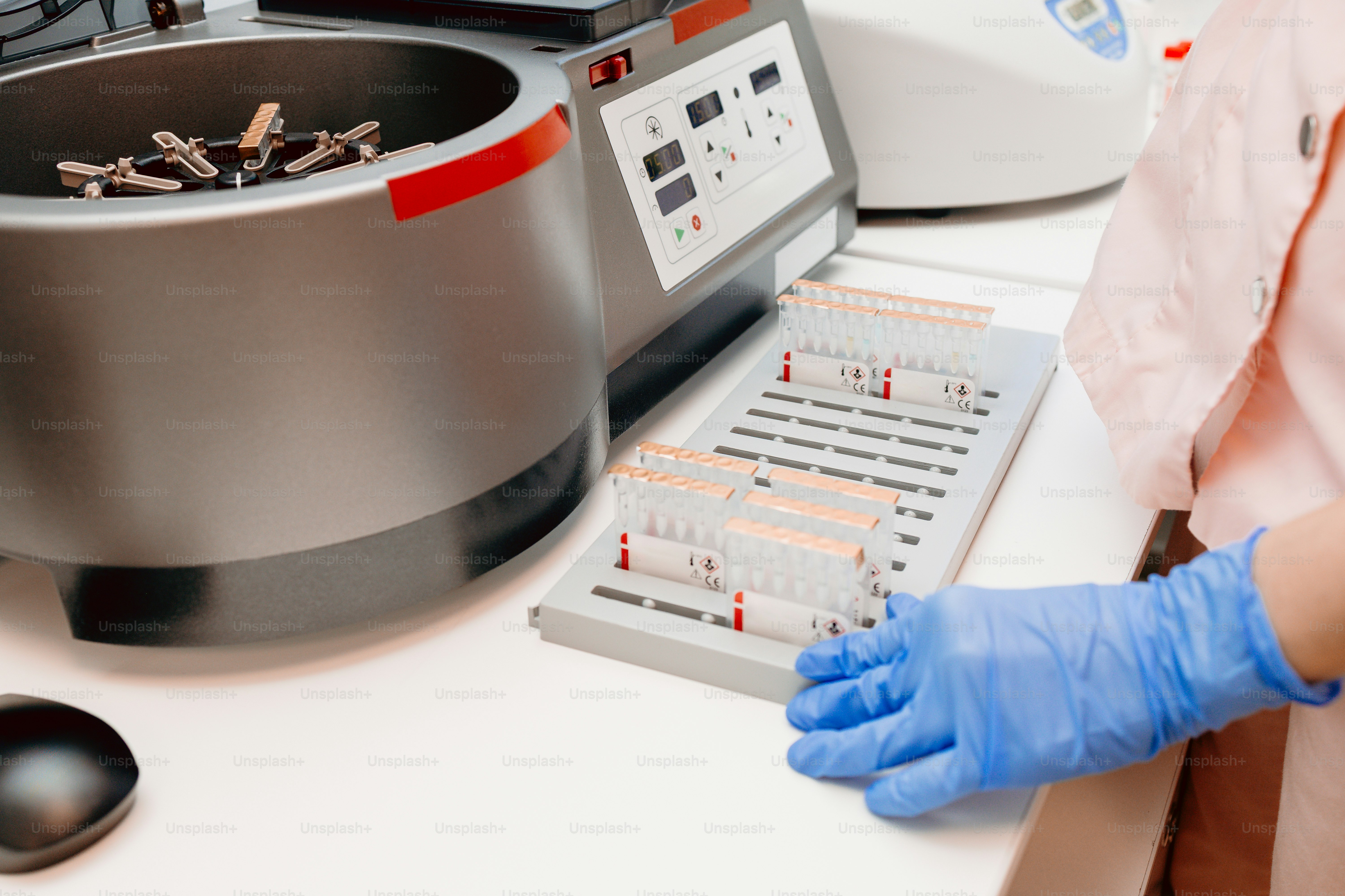 Person placing test tubes in centrifuge - Photo on Unsplash+