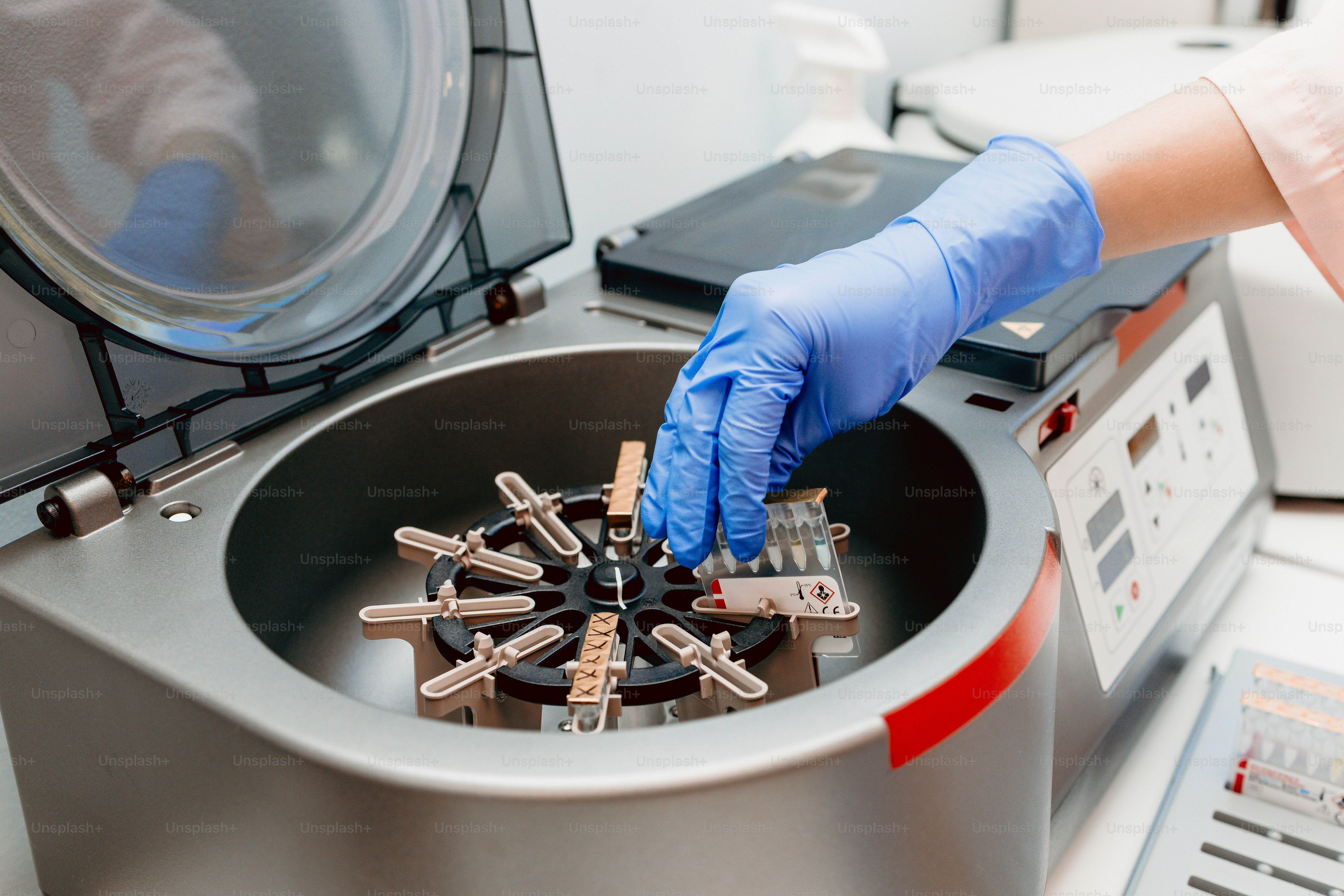 Person placing test tubes in centrifuge - Photo on Unsplash+