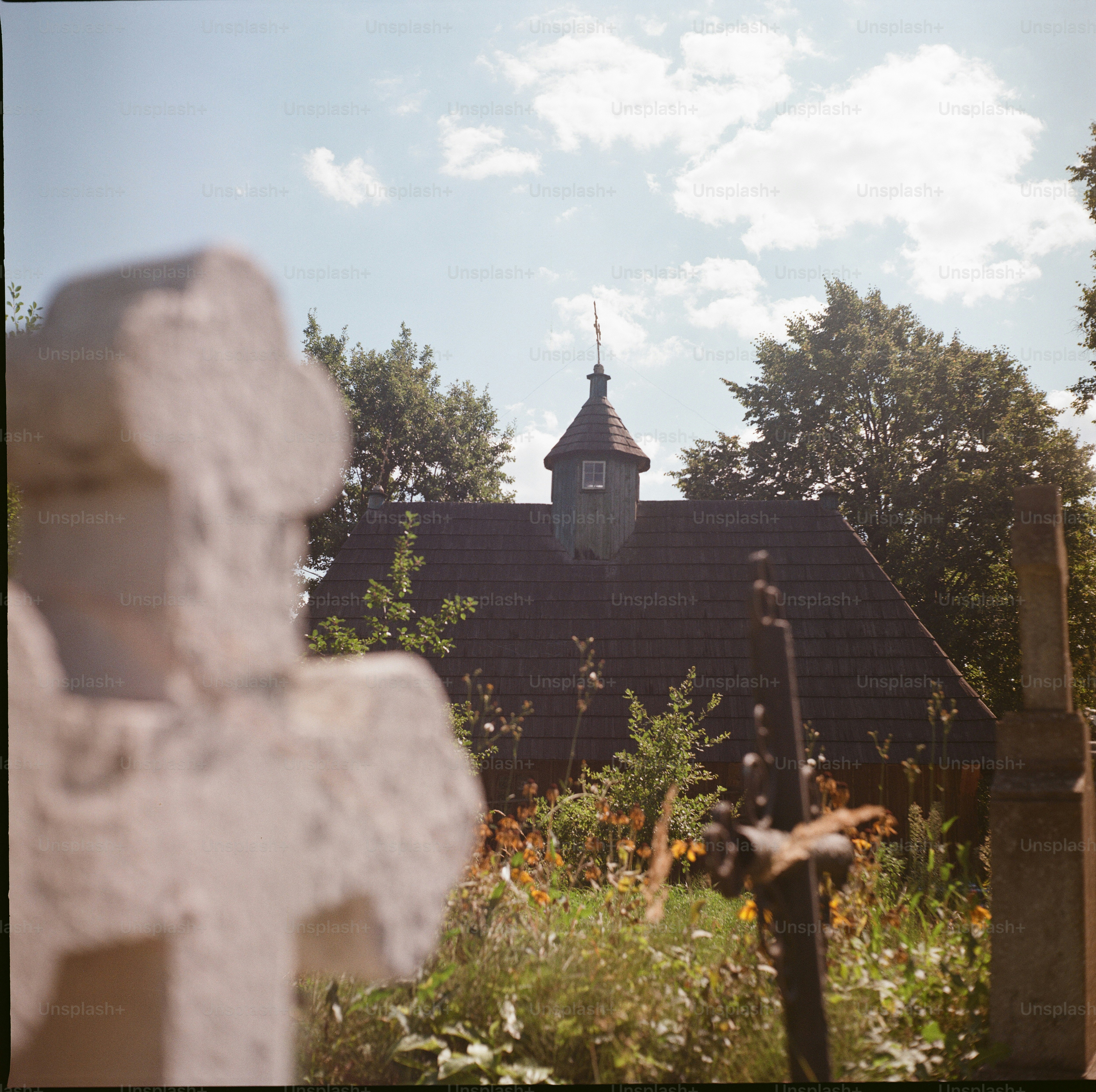 Wooden church behind cemetery crosses - Photo on Unsplash+