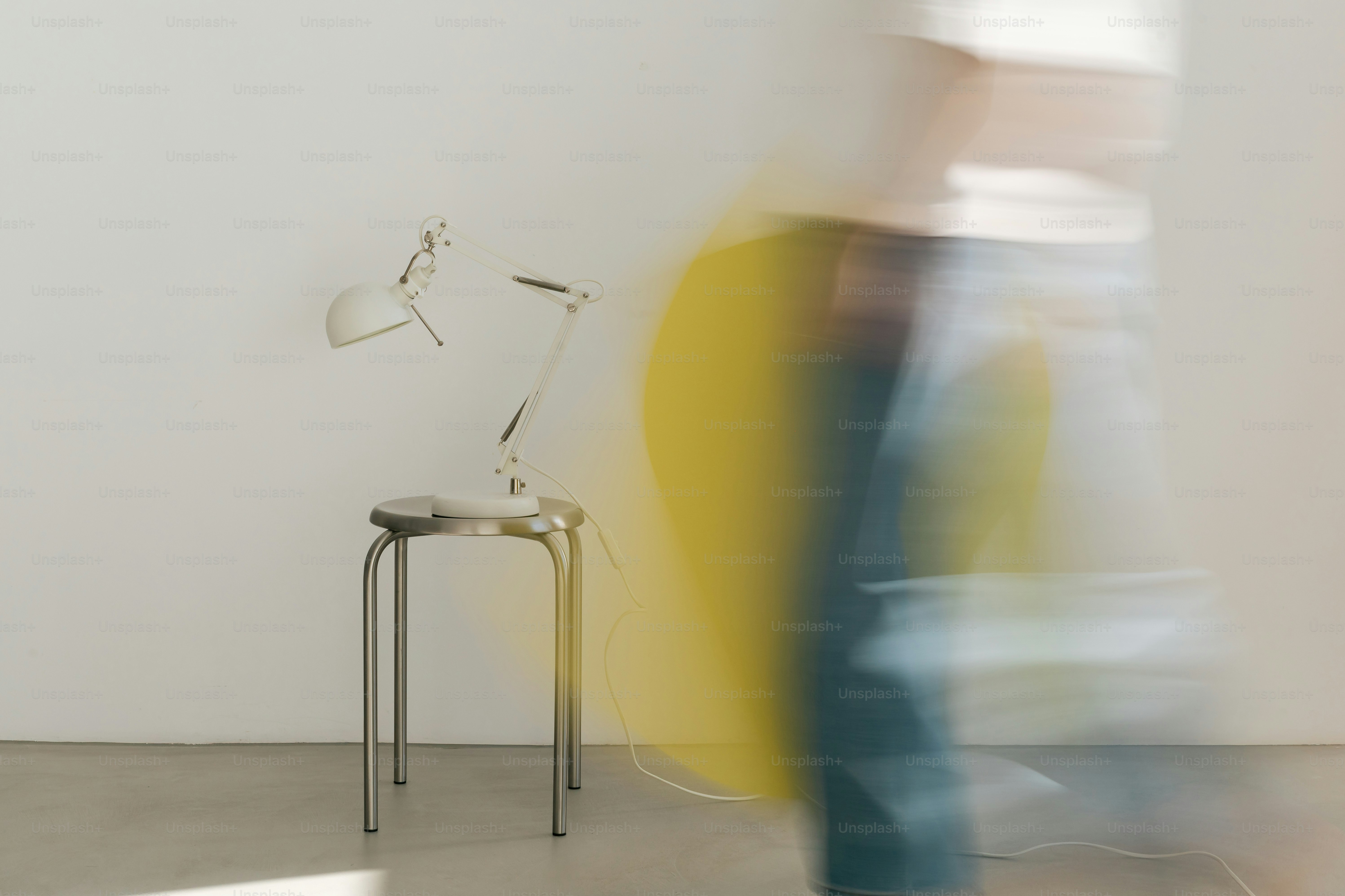 Person walking past lamp and stool - Photo on Unsplash+