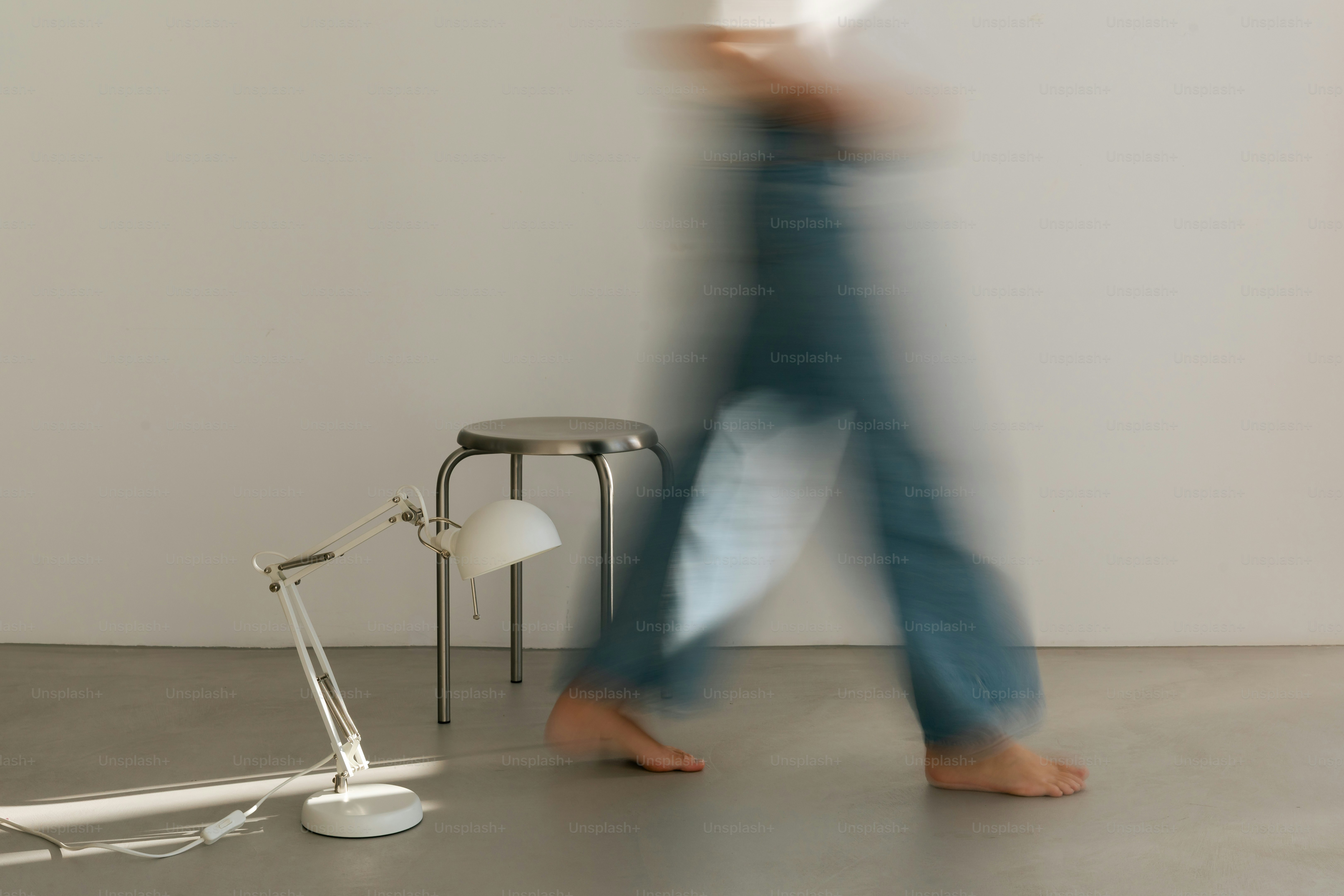 Person walking past lamp and stool - Photo on Unsplash+