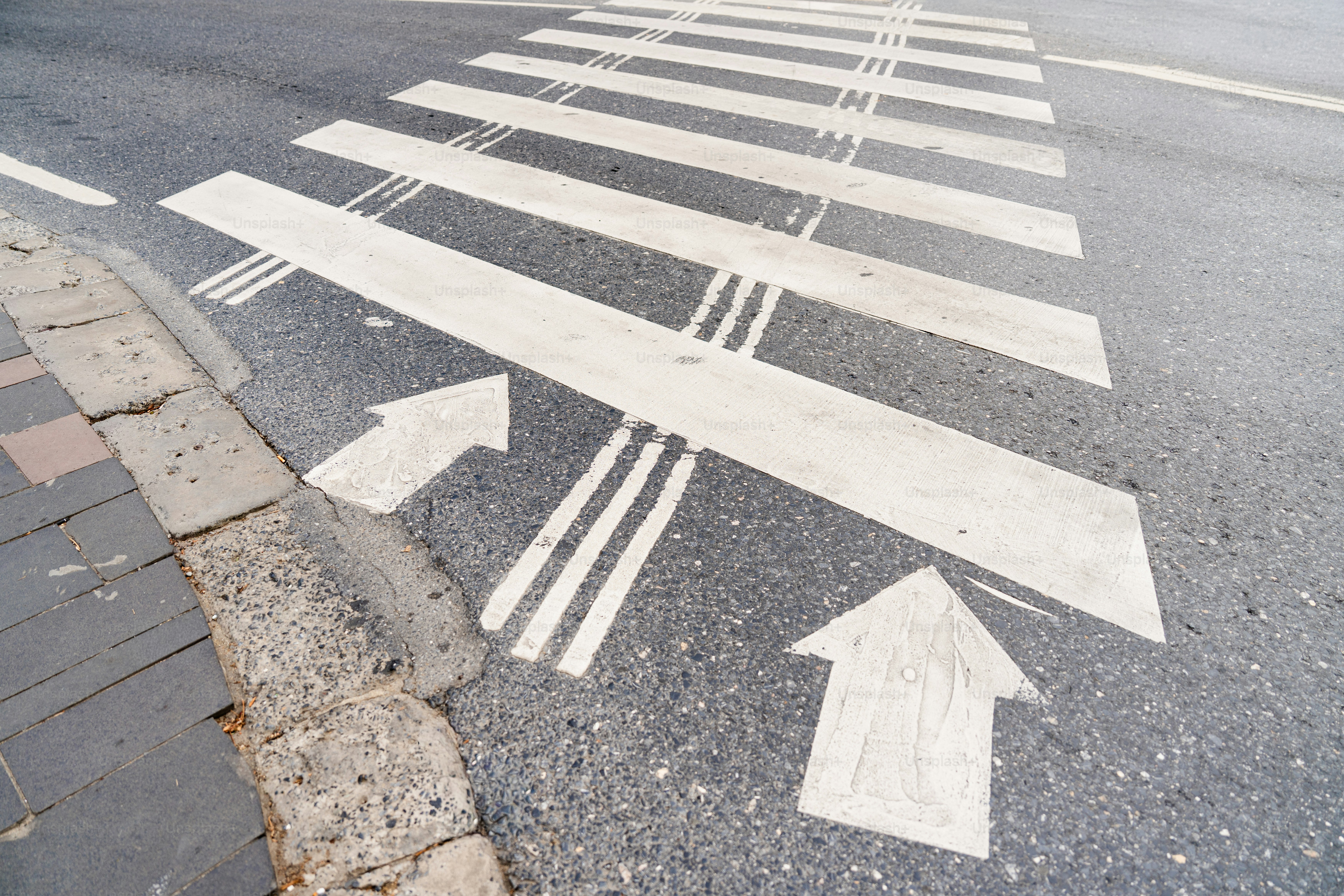 Two white arrows on asphalt - Photo on Unsplash+