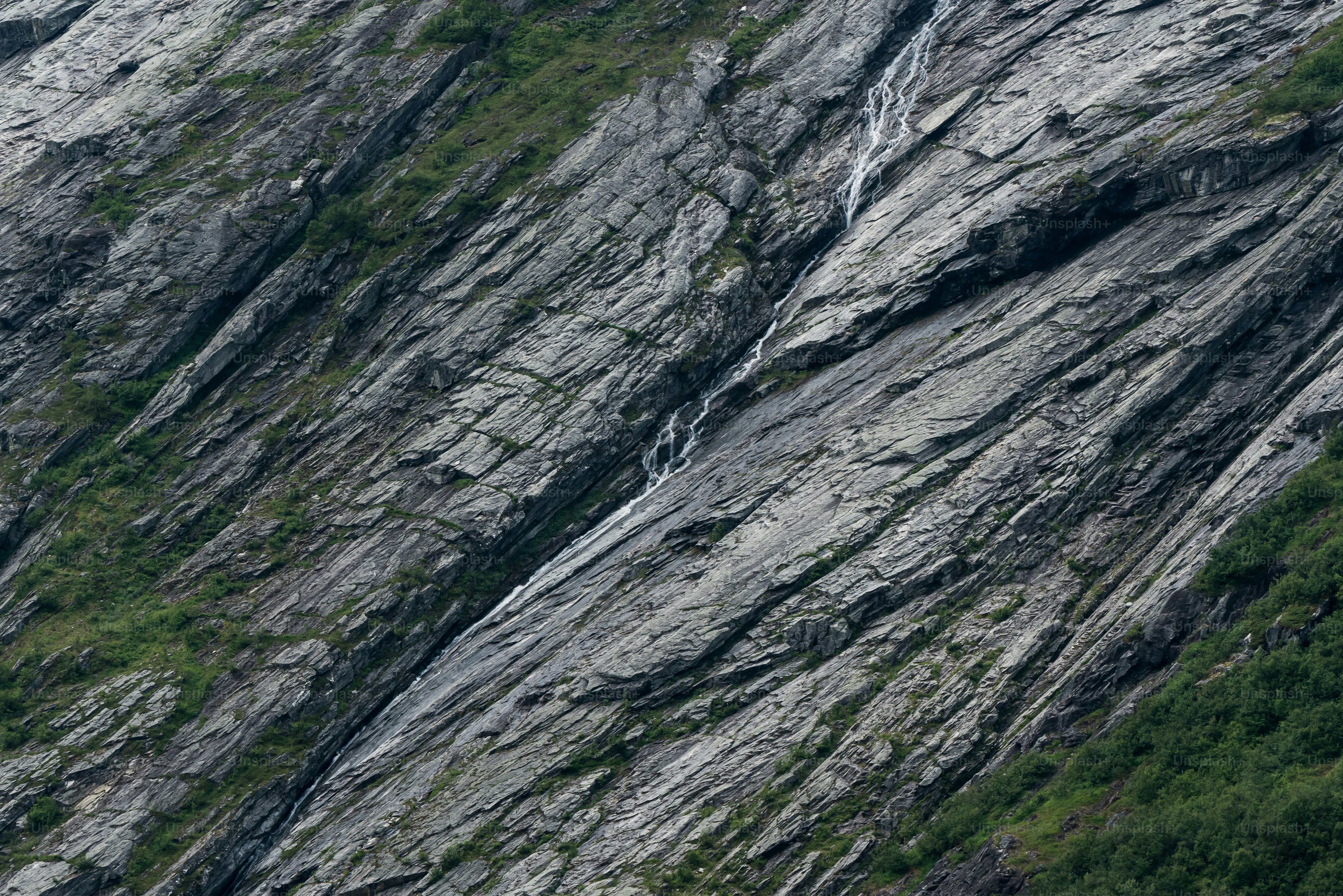 Waterfall on steep grey rock face - Photo on Unsplash+