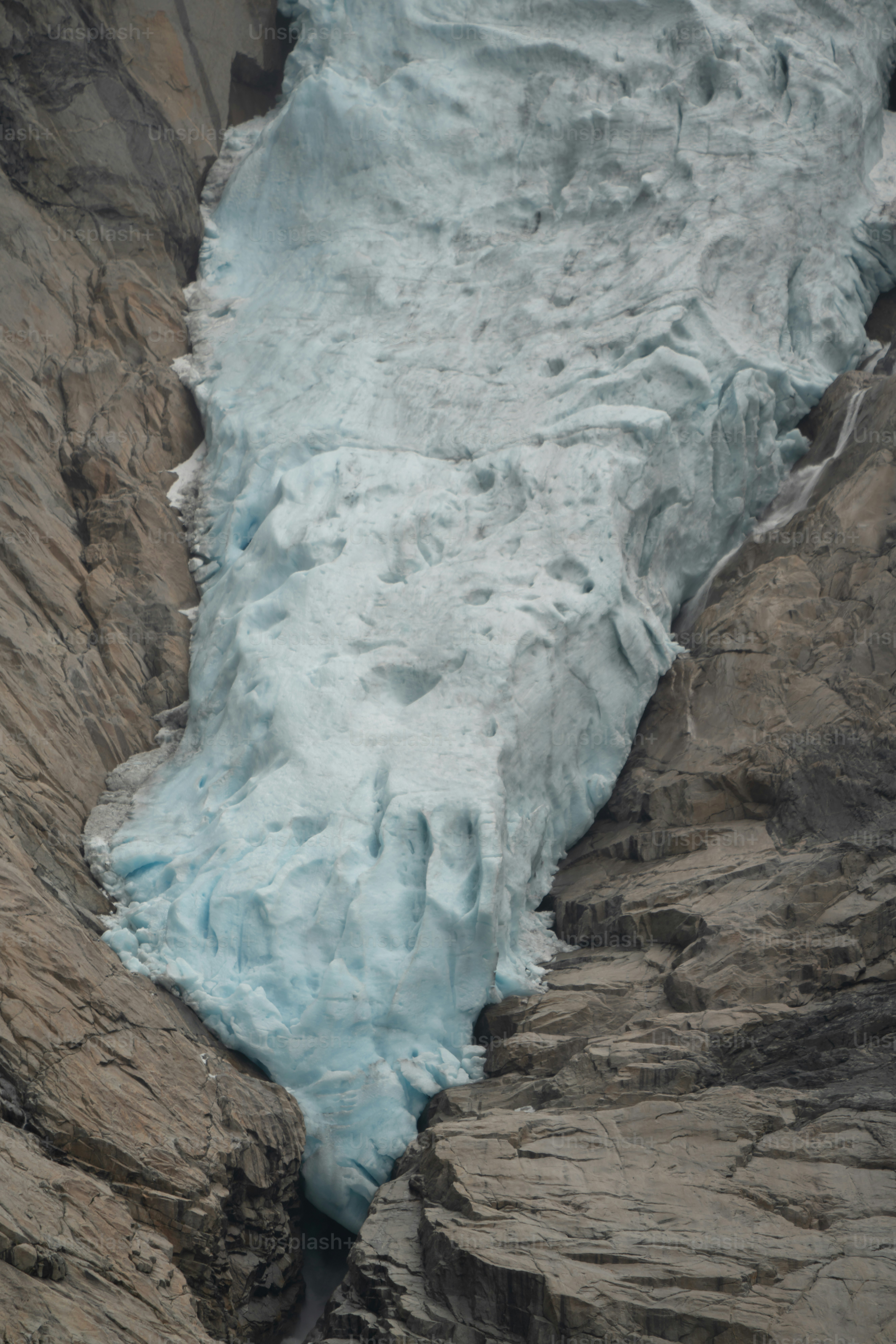 Blue glacier tongue between rocky walls - Photo on Unsplash+