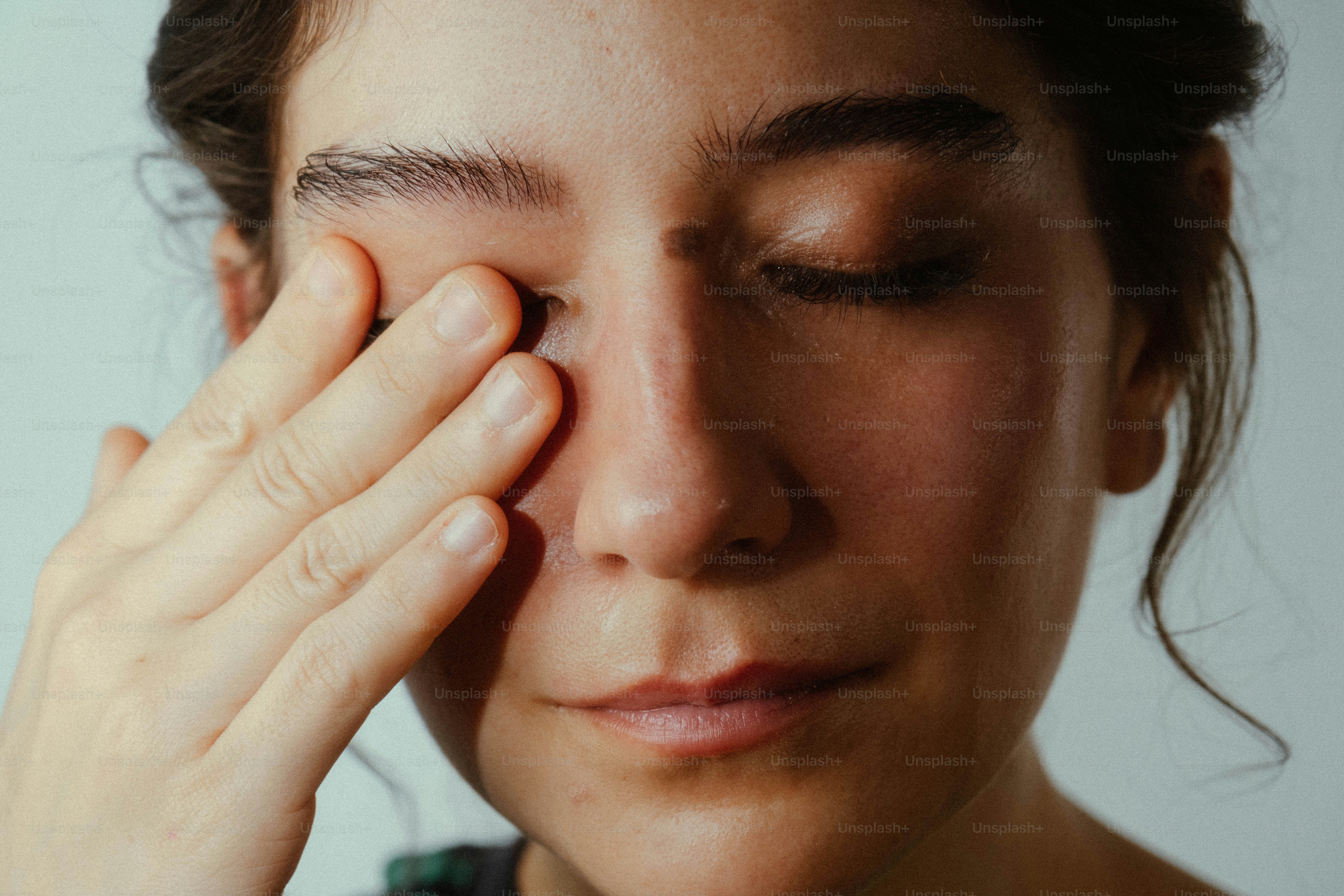 Woman rubbing eye on plain background - Photo on Unsplash+