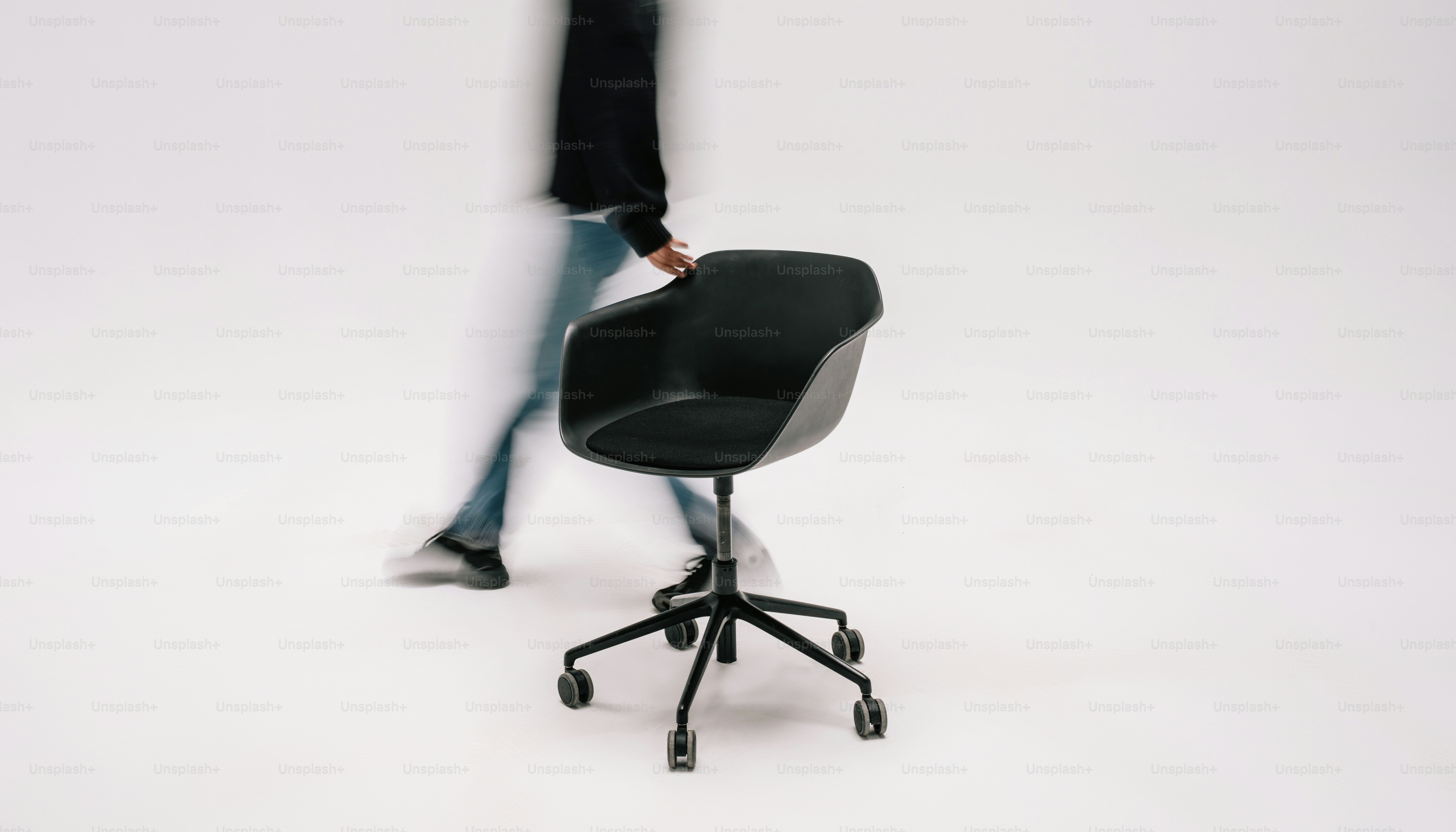 Person walking past black office chair - Photo on Unsplash+