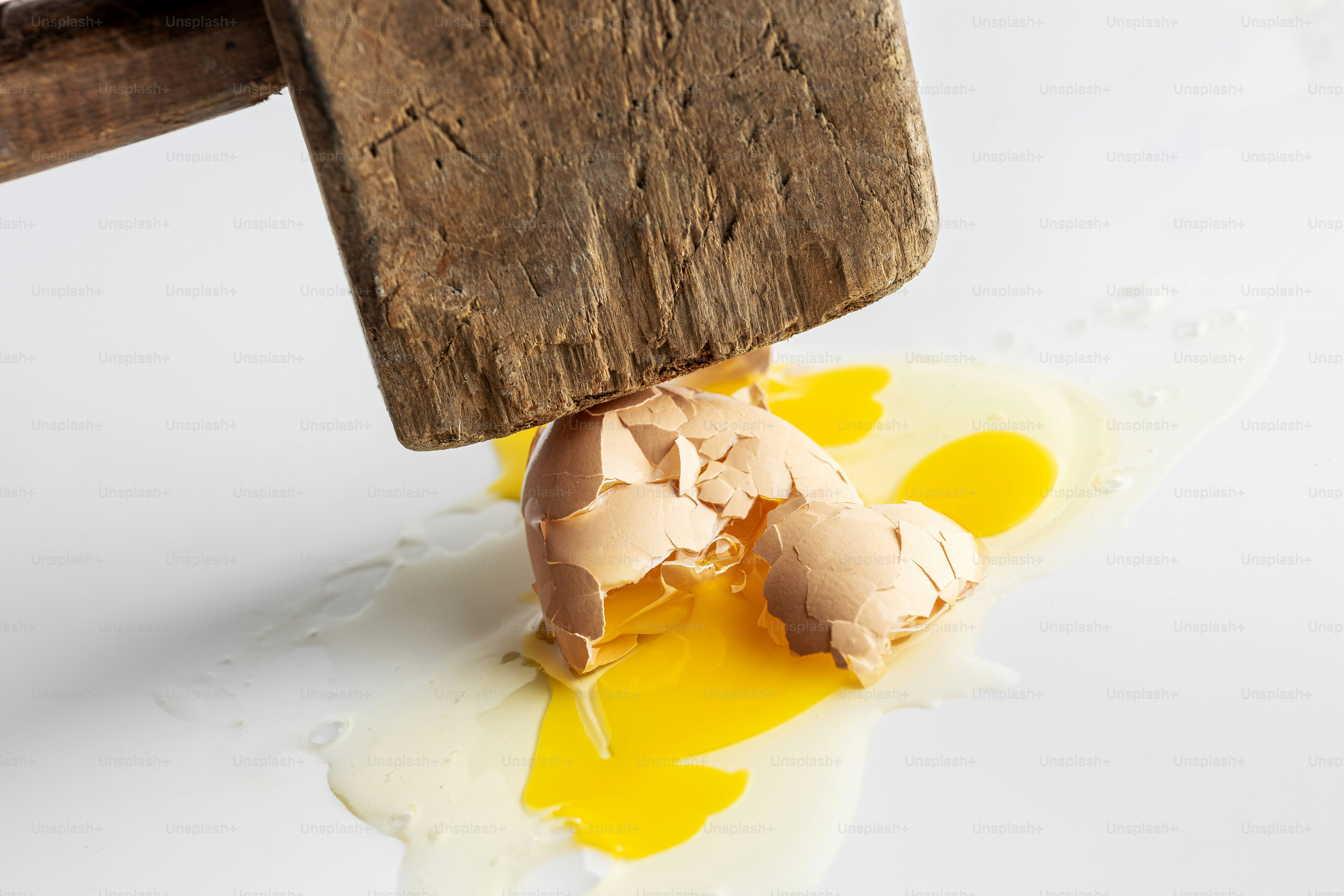 Wooden mallet crushing brown egg - Photo on Unsplash+